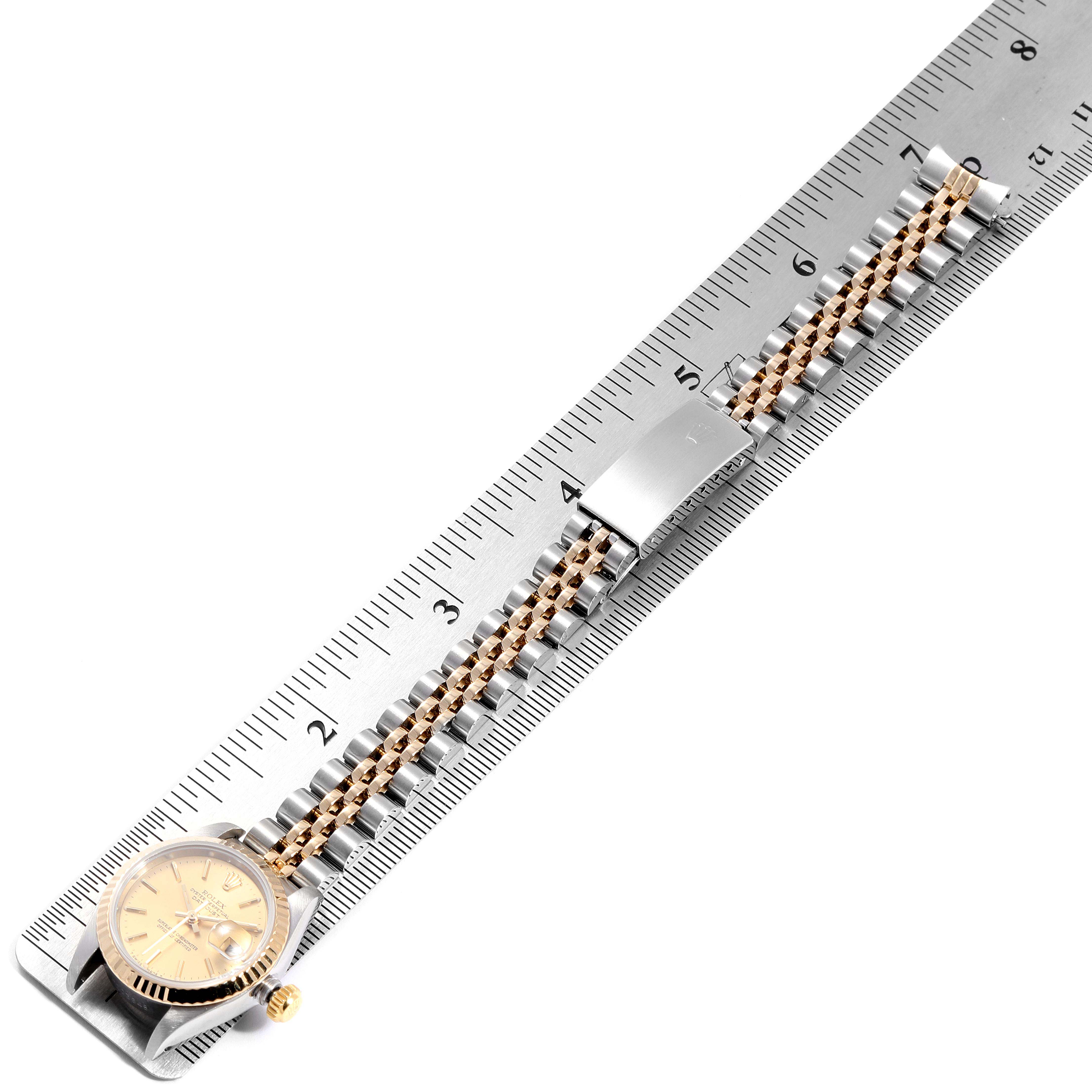This image shows a Rolex Datejust 69173 Women's Steel and Gold (two tone) Champagne Dial 69173 Women's Steel and Gold (two tone) Champagne Dial watch lying flat on a ruler, displaying its band and face.