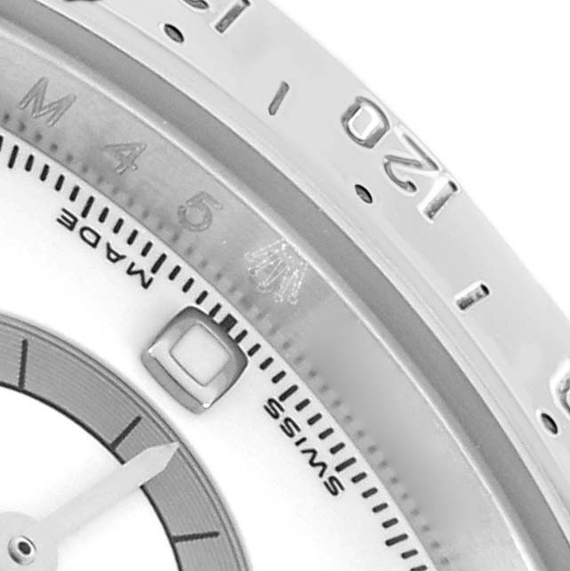 The image shows a close-up of the Rolex Daytona 116520 Men's Stainless Steel White Dial watch face, highlighting the bezel, part of the dial, and a subdial marker.