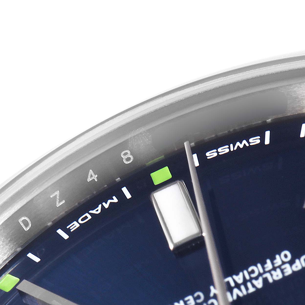 This image shows a close-up of the dial and the edge of the bezel of a Rolex Oyster Perpetual 114300 Men's Stainless Steel Blue Dial 114300 Men's Stainless Steel Blue Dial watch.