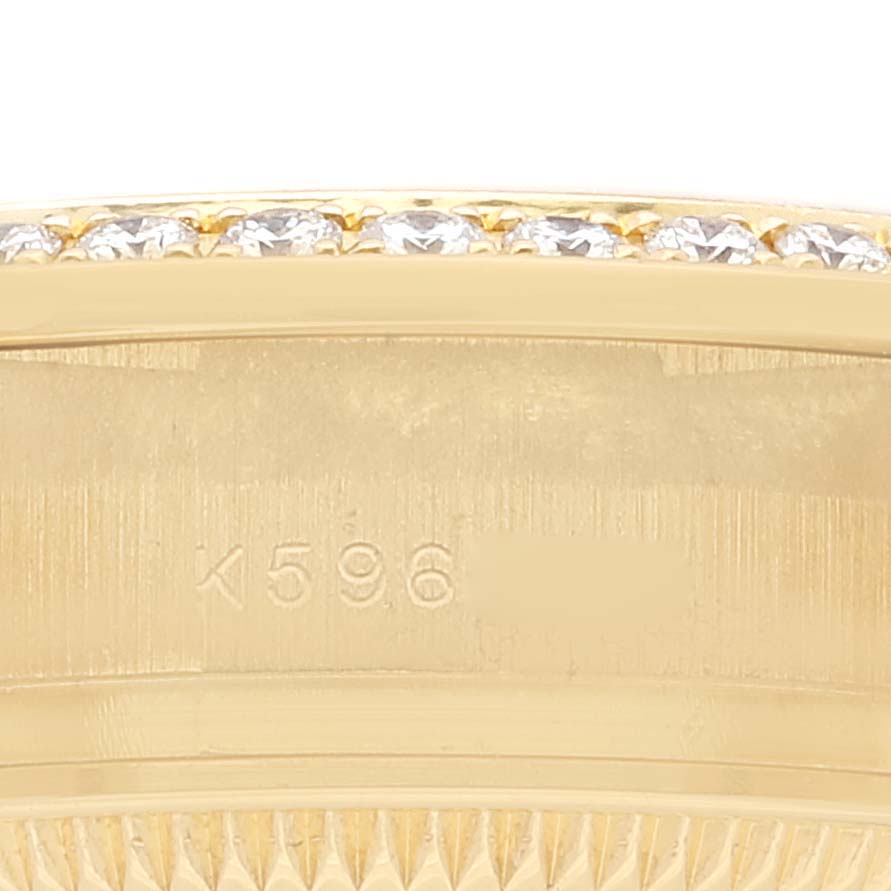 This close-up image shows the side view of a Rolex President 179158 Women's Yellow Gold Silver Dial 179158 Women's Yellow Gold Silver Dial watch bezel with diamonds and an engraved serial number.