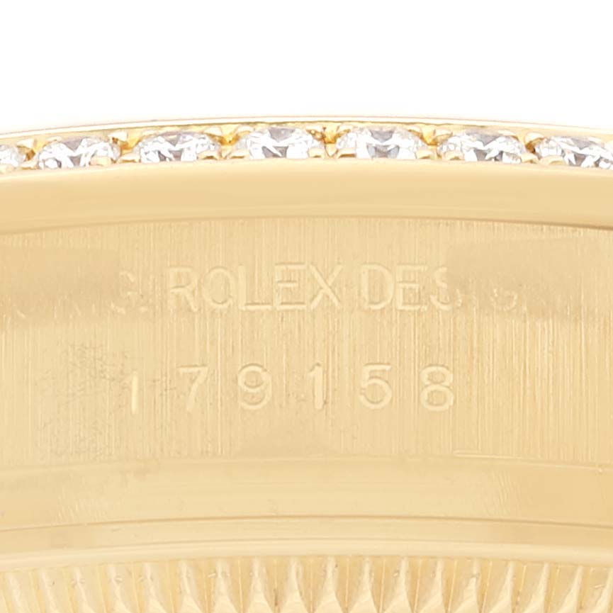 This close-up image of a Rolex President 179158 Women's Yellow Gold Silver Dial 179158 Women's Yellow Gold Silver Dial watch shows the case and part of the bezel with diamonds.