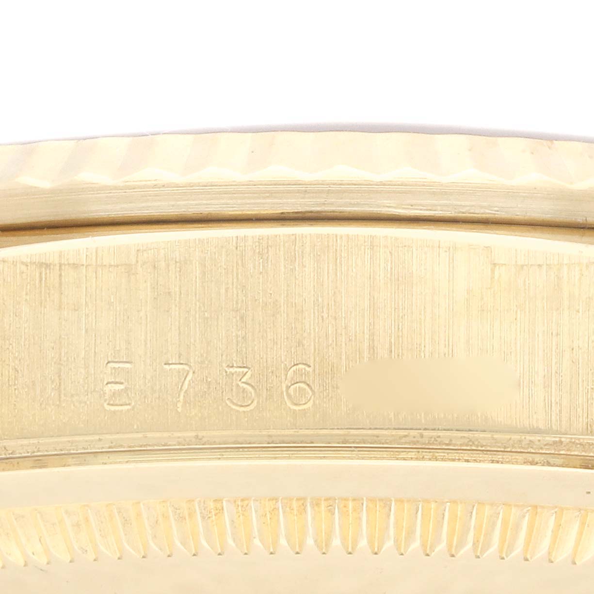 This close-up of the Rolex President 18238 Men's Yellow Gold White Dial 18238 Men's Yellow Gold White Dial model watch shows the side of the bezel and part of the case with an engraved serial number.