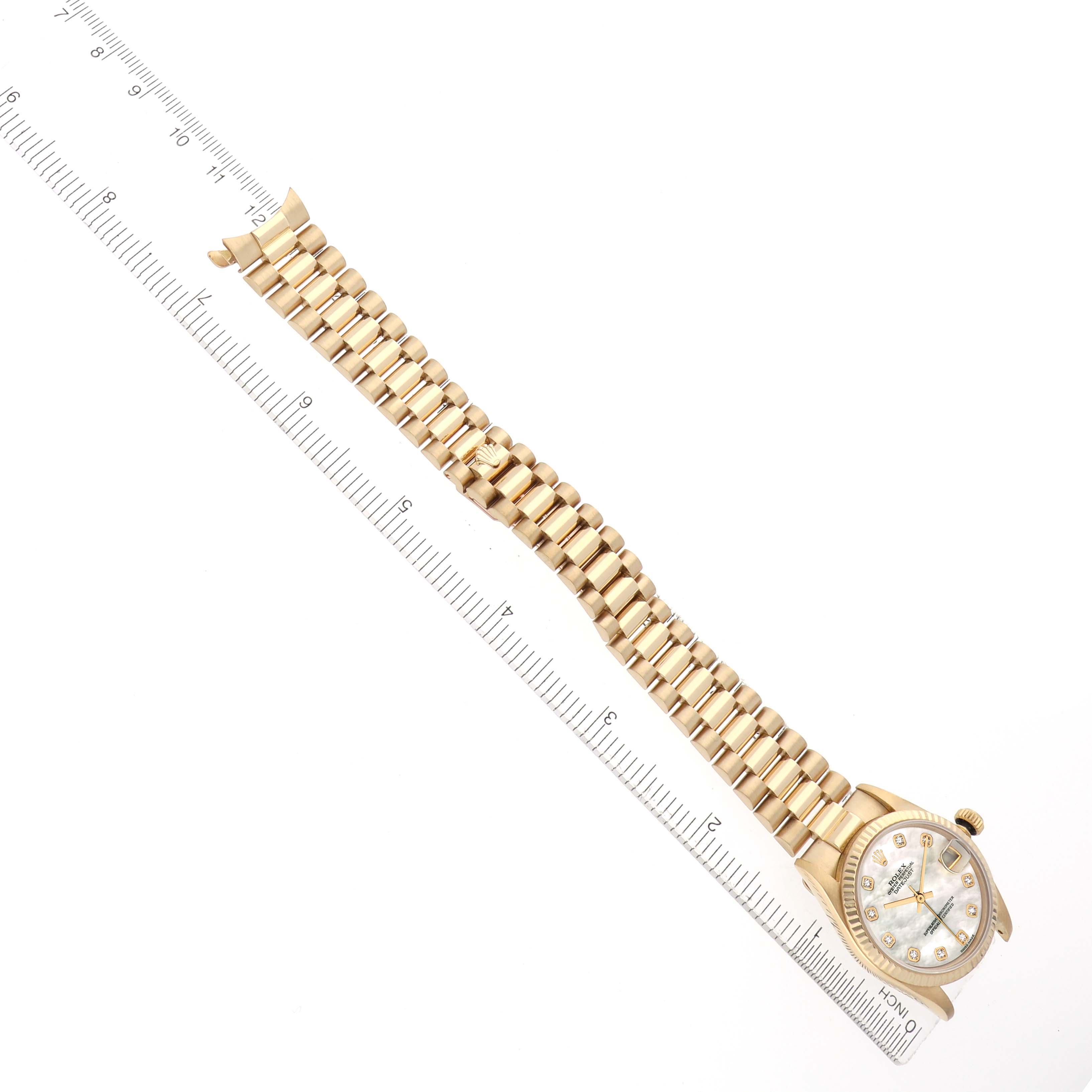 The Rolex President 68278 Women
s Yellow Gold Mother of Pearl Dial watch is shown diagonally, focusing on its bracelet, case, and dial, alongside a ruler for scale.