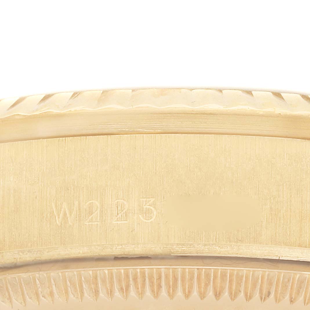 The image shows a close-up of the side and edge of a Rolex President 68278 Women
s Yellow Gold Mother of Pearl Dial model case, highlighting its serrated bezel and engraved serial number.