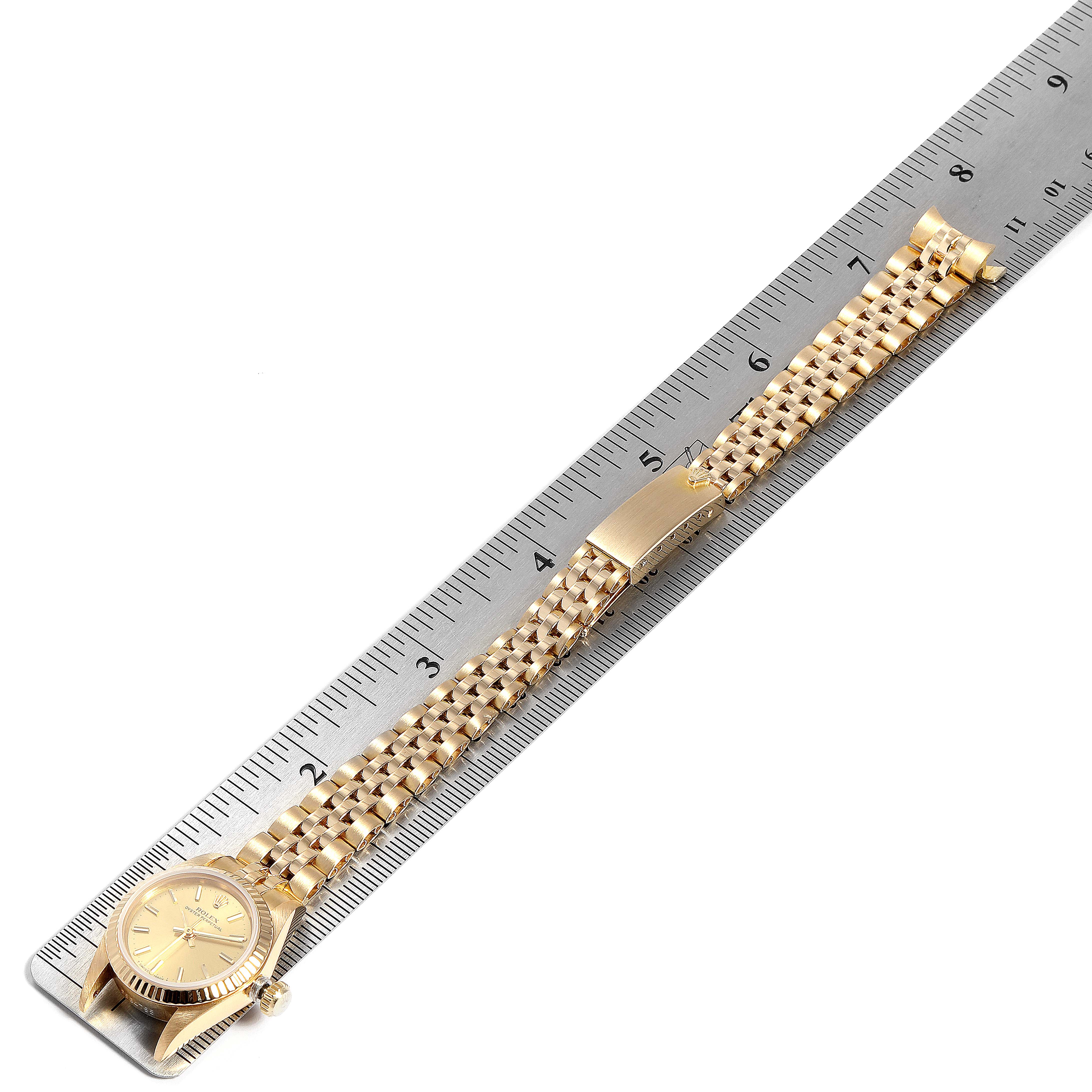 The Rolex President 67198 Women
s Yellow Gold Champagne Dial 67198 Women
s Yellow Gold Champagne Dial model watch is shown from a top-down angle, displaying its face, bracelet, and clasp next to a ruler for scale.