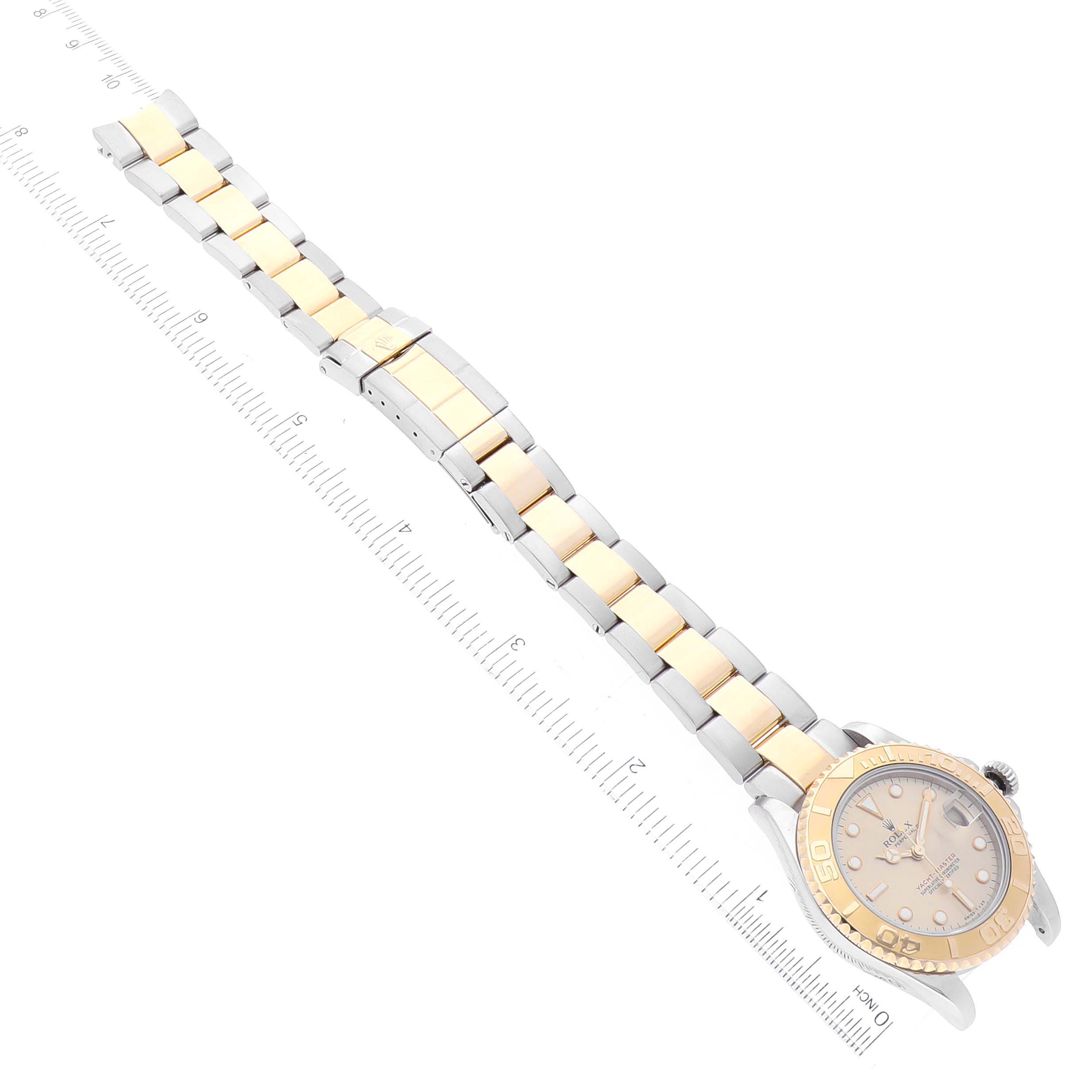 The Rolex Yacht-Master 68623 Men
s Steel and Gold (two tone) Champagne Dial 68623 Men
s Steel and Gold (two tone) Champagne Dial watch is displayed at a slight angle, showing the watchface, bezel, and full bracelet with a ruler alongside.