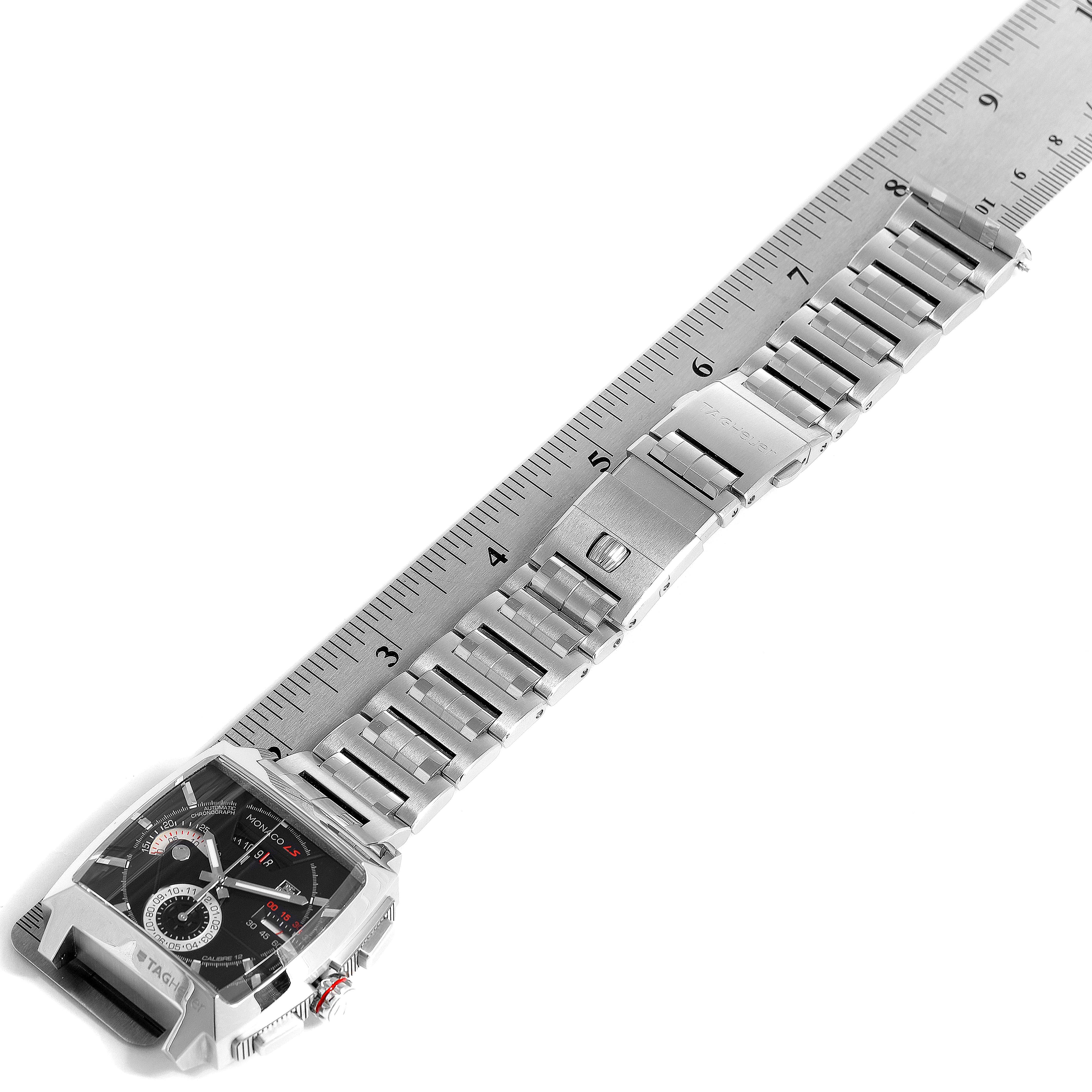 The image shows the Tag Heuer Monaco CAL2110.BA0781 Men's Stainless Steel Black Dial CAL2110.BA0781 Men's Stainless Steel Black Dial watch laid flat along a ruler, showcasing its face and metal bracelet.