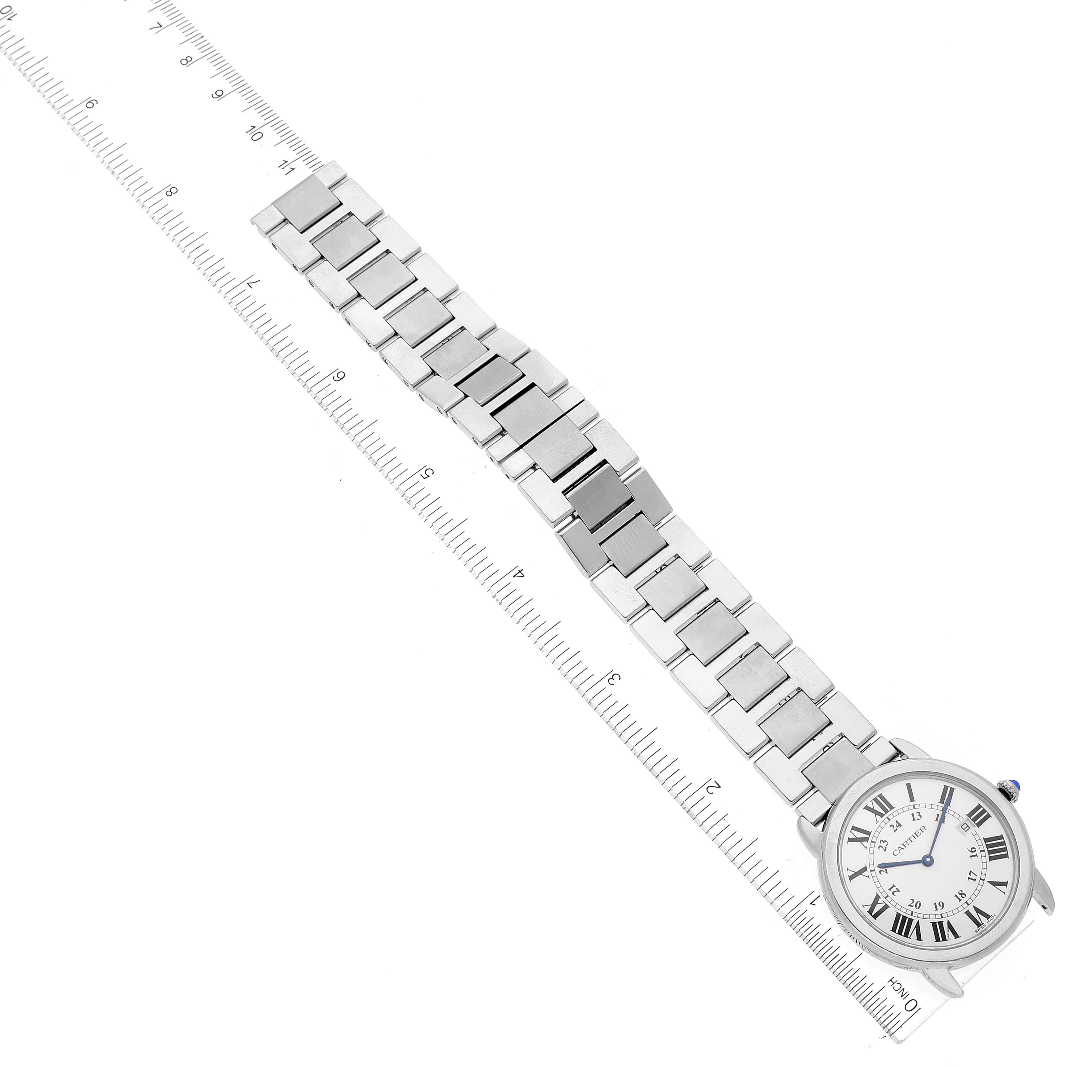 The image shows an overhead view of a Cartier Ronde W6701005 Men
s Stainless Steel Silver Dial W6701005 Men
s Stainless Steel Silver Dial watch, showcasing the face and metal bracelet beside a ruler.