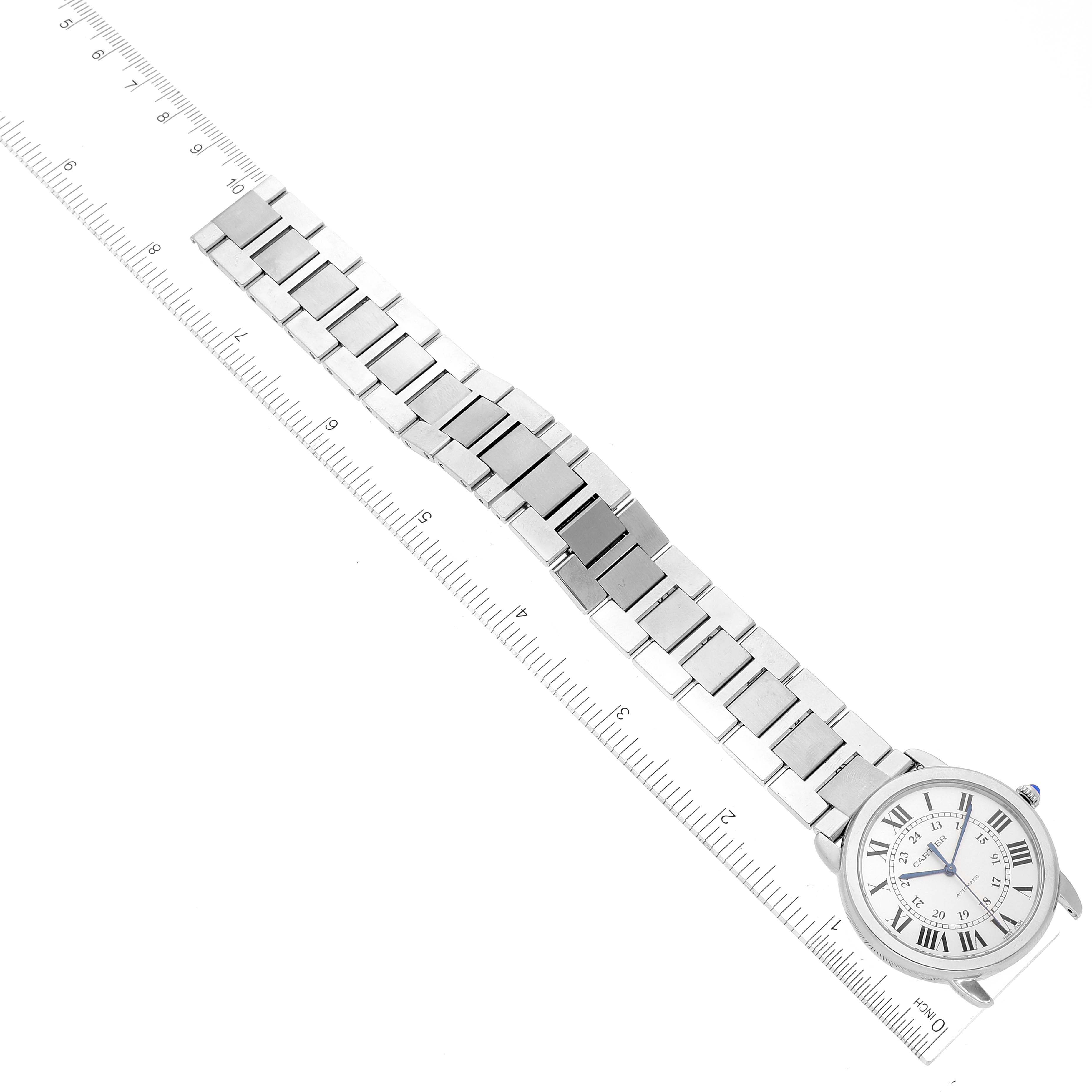 This image shows a full view from above of the Ronde model by Cartier, including the watch face and metal bracelet, alongside a ruler.