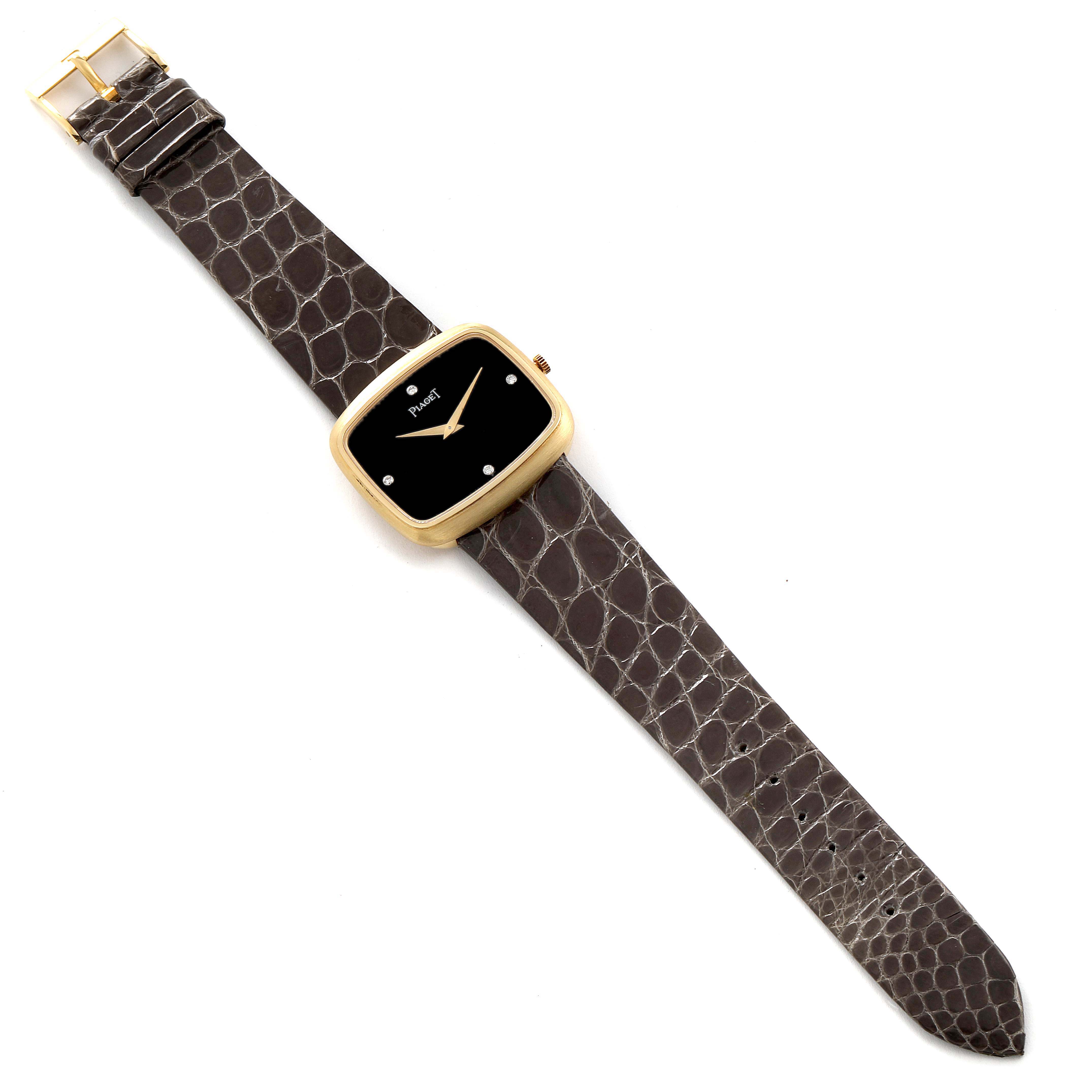 The Piaget 9751 Men's Yellow Gold Black Dial 9751 Men's Yellow Gold Black Dial 9751 model watch is shown from a top-down angle, displaying its 18K yellow gold case, black diamond dial, and grey strap.