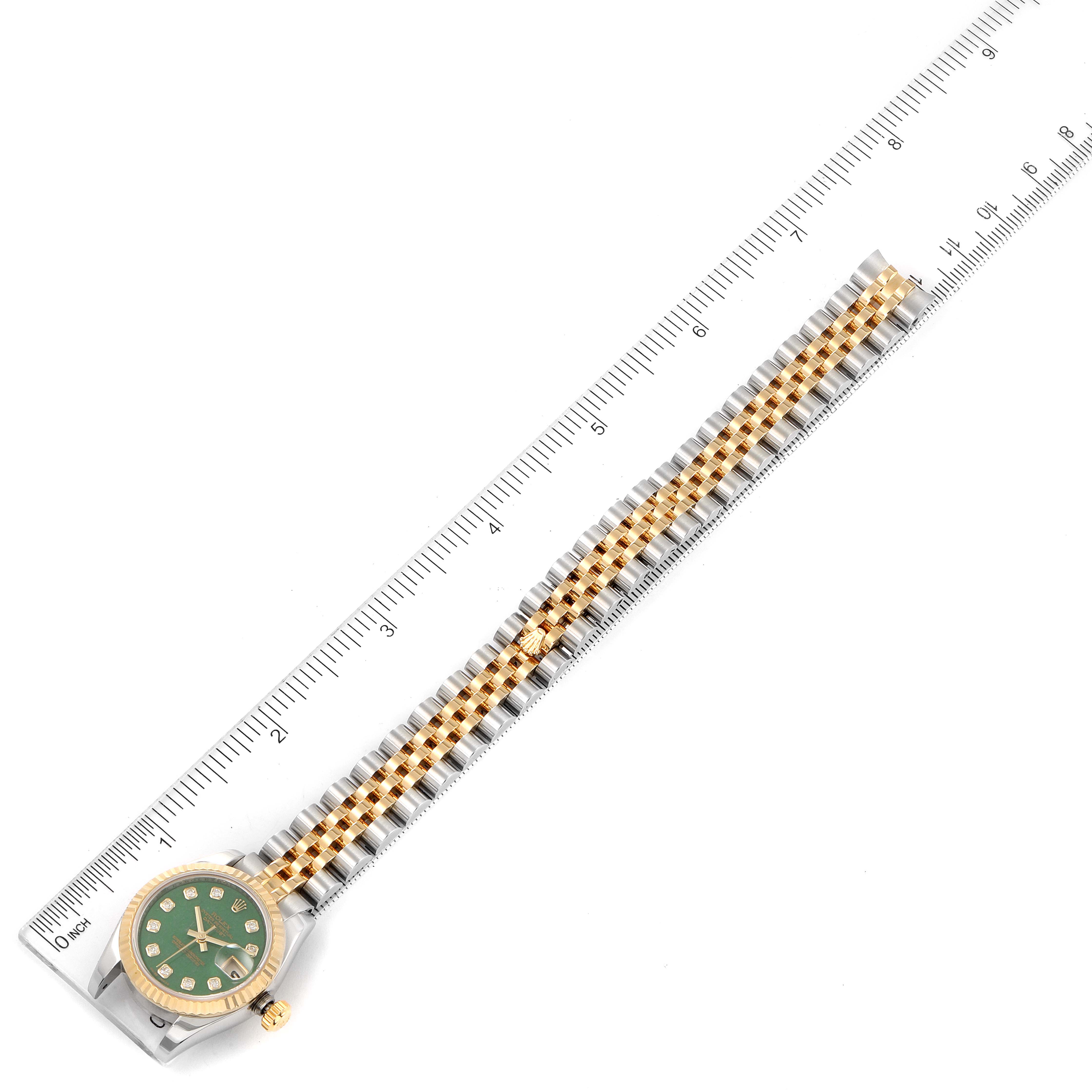 The Rolex Datejust 179173 Women's Steel and Gold (two tone) Green Dial 179173 Women's Steel and Gold (two tone) Green Dial watch is shown from an overhead angle, displaying the full face and bracelet against a ruler for scale.