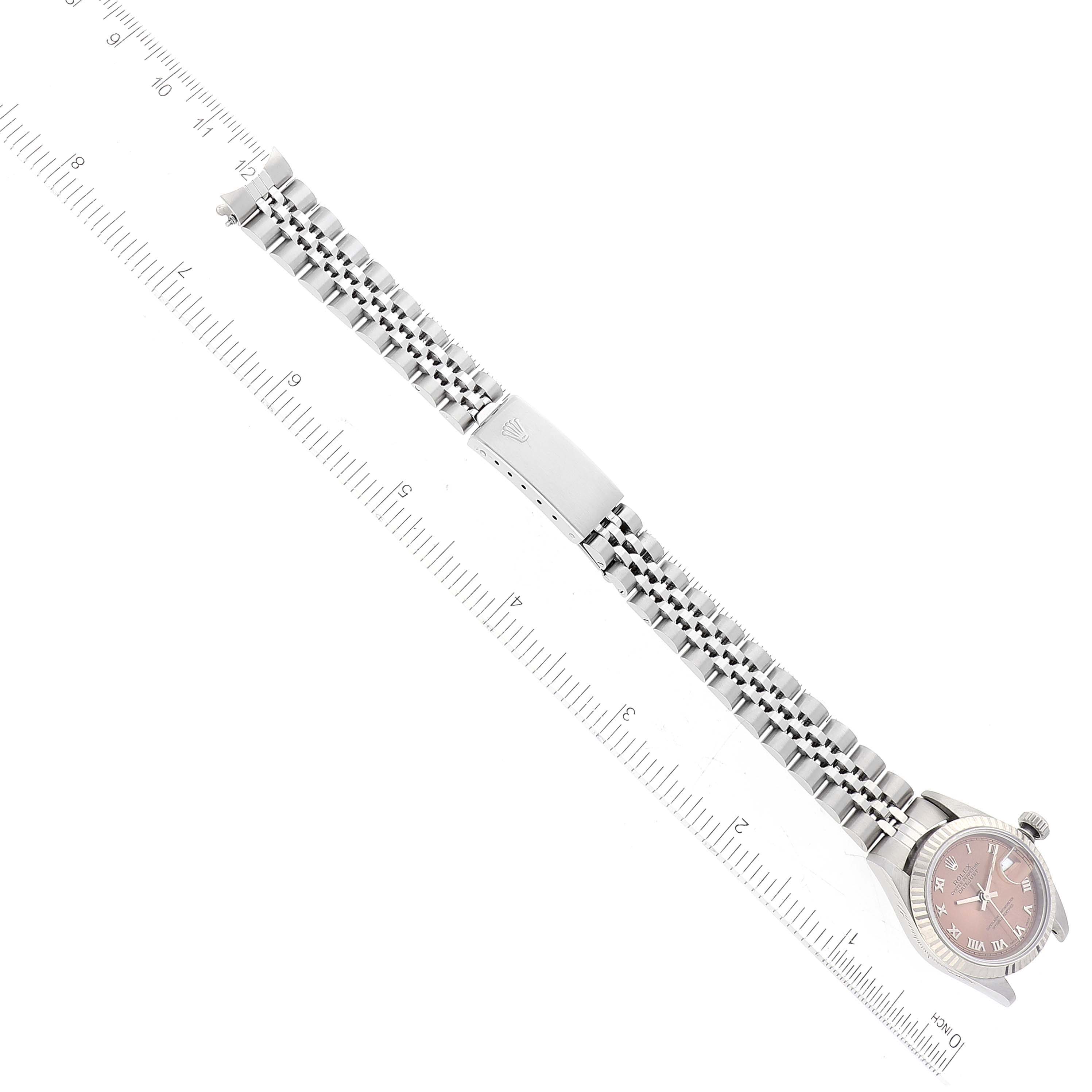 The Rolex Datejust 69174 Women's Stainless Steel Pink Dial 69174 Women's Stainless Steel Pink Dial watch is shown from an aerial view, displaying its metal bracelet and clasp along with a ruler for scale.
