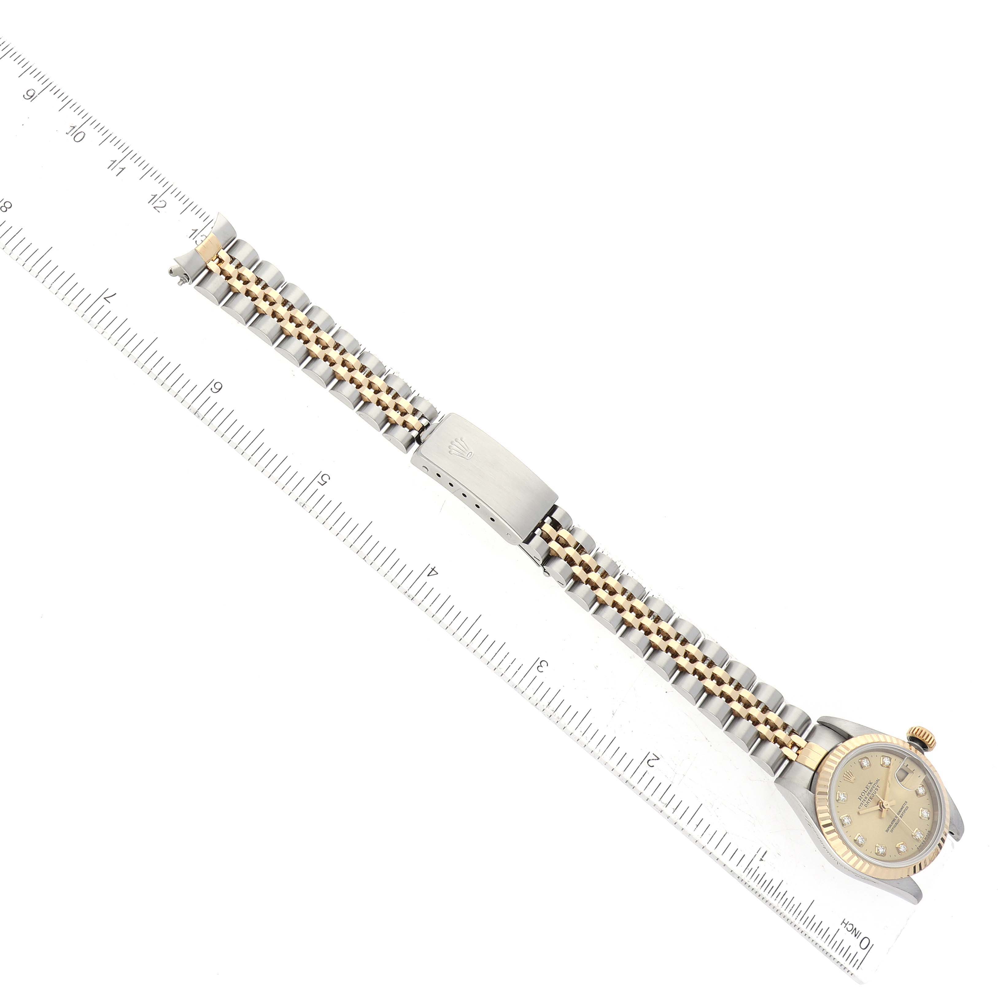 This image shows a Rolex Datejust 79173 Women's Steel and Gold (two tone) Champagne Dial 79173 Women's Steel and Gold (two tone) Champagne Dial watch, including its dial, bezel, and the full length of its metal bracelet, next to a ruler for scale.