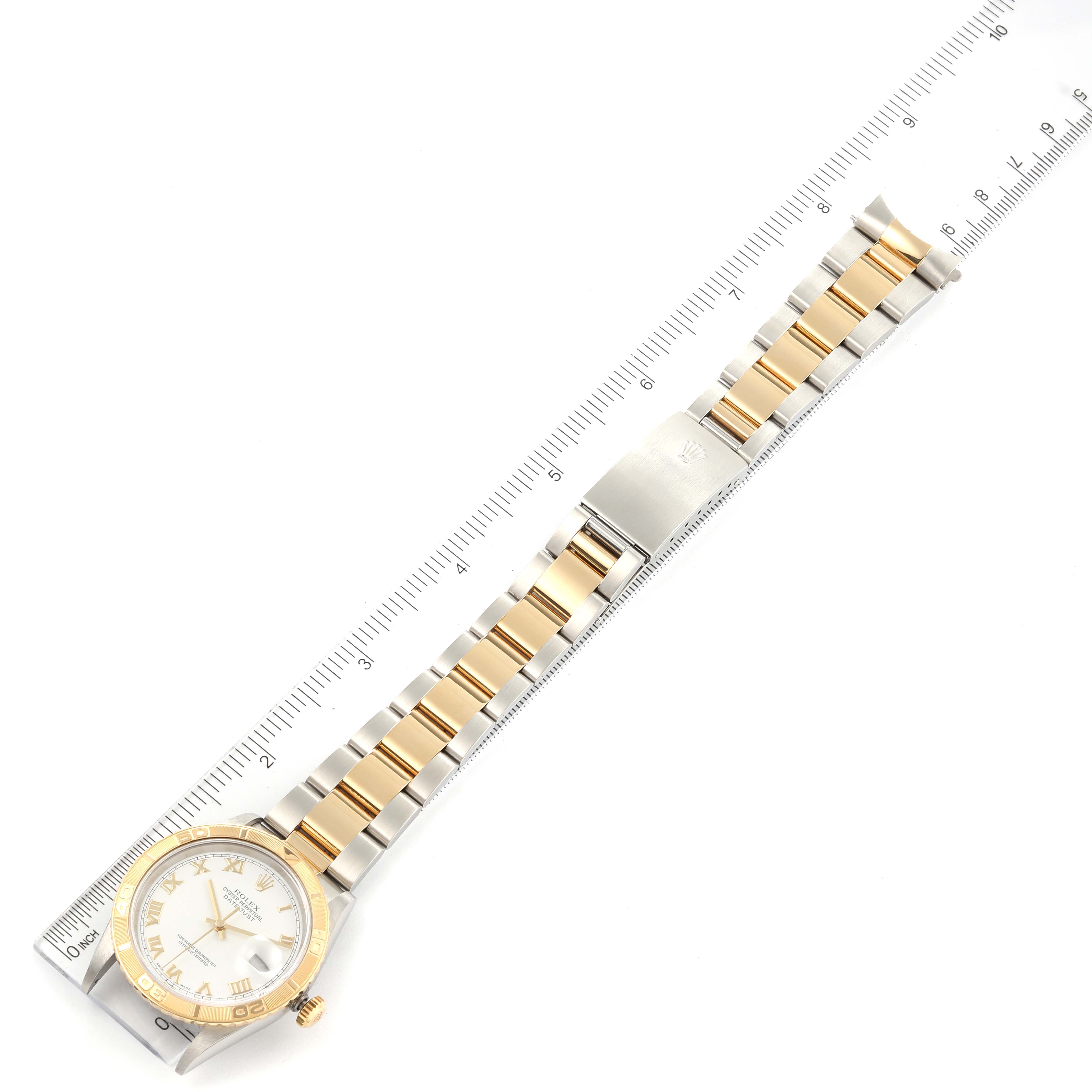 The Rolex Turn-o-Graph 16263 Men
s Steel and Gold (two tone) White Dial 16263 Men
s Steel and Gold (two tone) White Dial watch is shown from a top-down angle, displaying the face, bezel, and full bracelet alongside a measuring ruler.