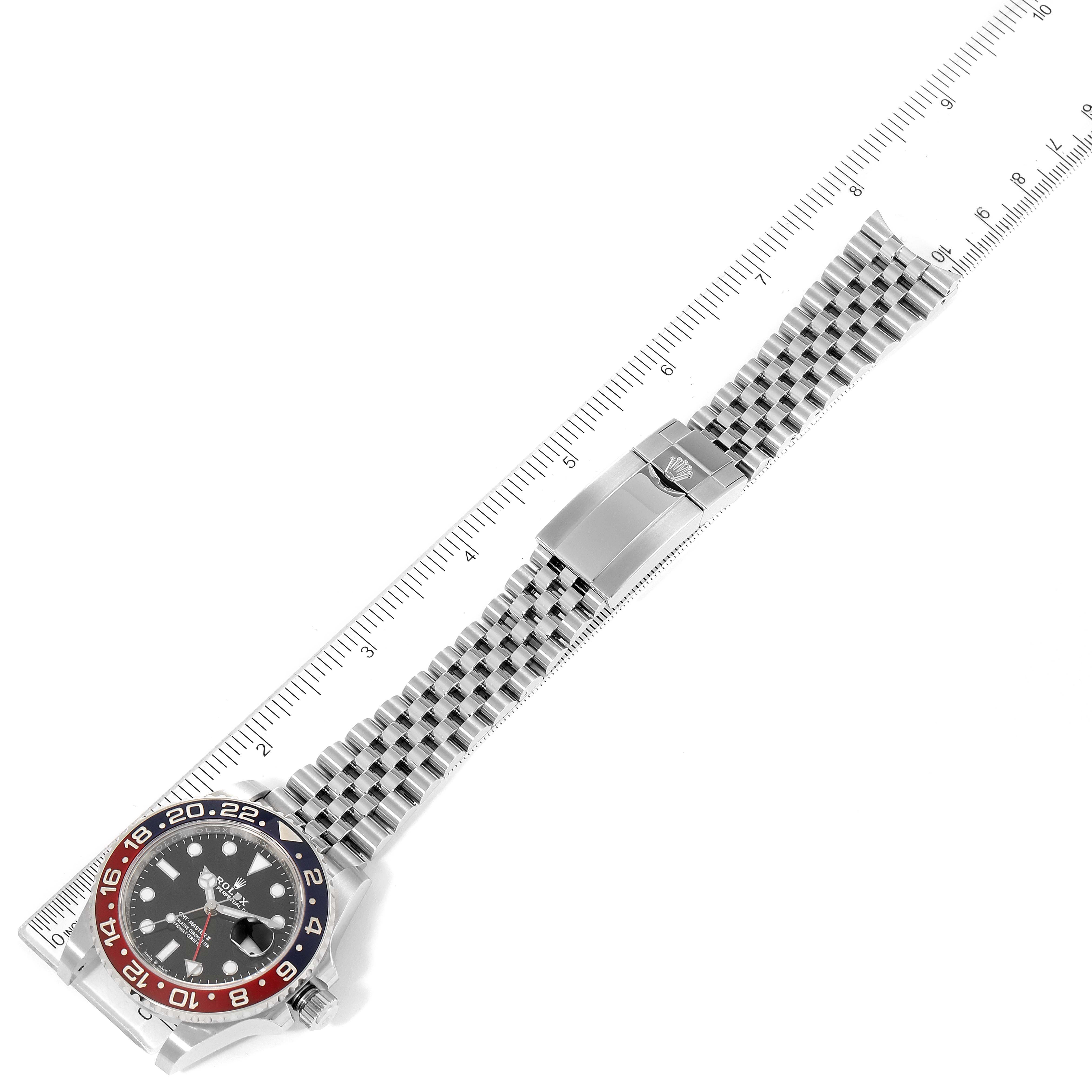 The image shows a top view of a Rolex GMT-Master 126710 Men
s Stainless Steel Black Dial 126710 Men
s Stainless Steel Black Dial watch, highlighting the full bracelet and watch face placed next to a ruler.