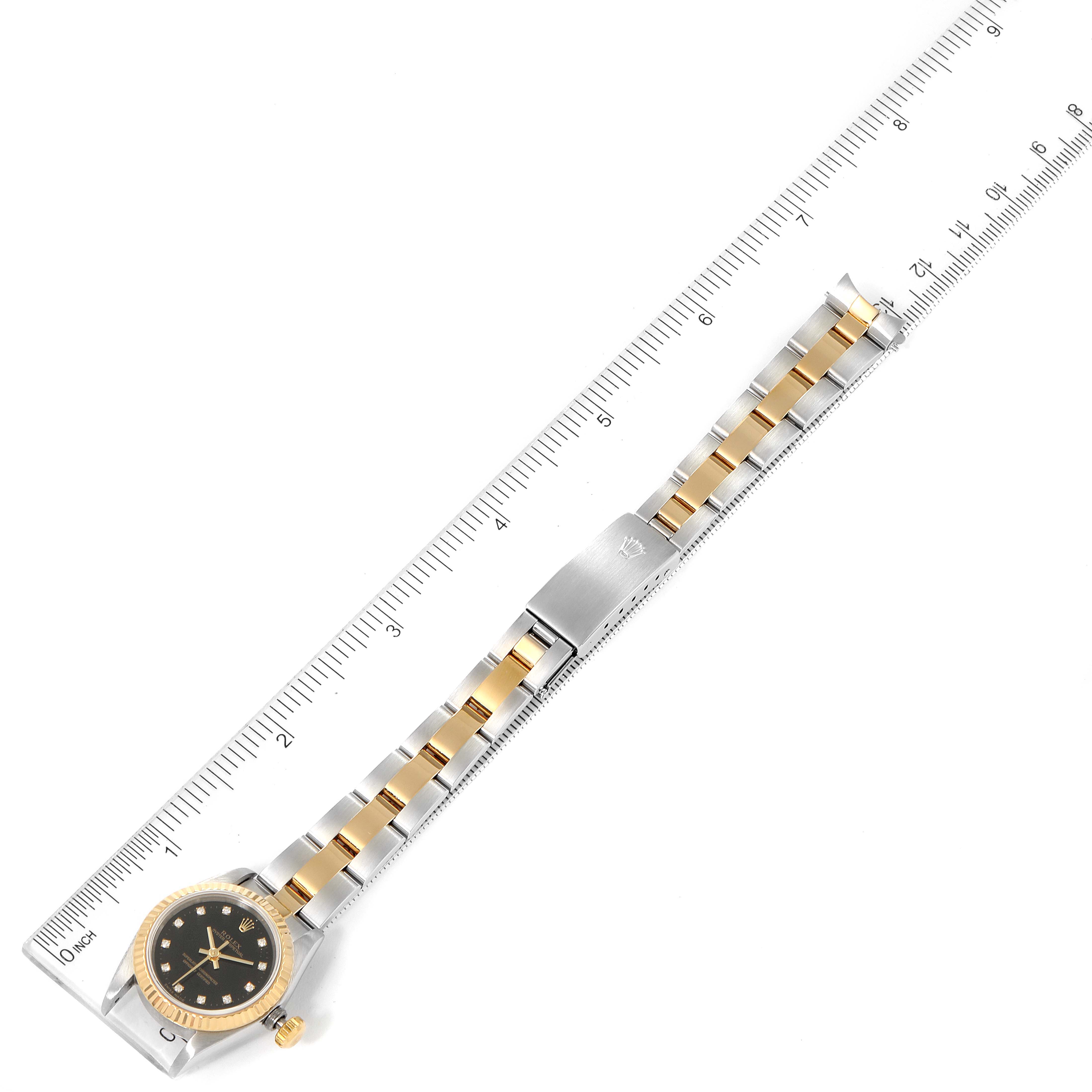 The image shows a Rolex Oyster Perpetual 67193 Women's Steel and Gold (two tone) Black Dial 67193 Women's Steel and Gold (two tone) Black Dial watch laid flat next to a ruler, displaying the dial, bezel, and bracelet.