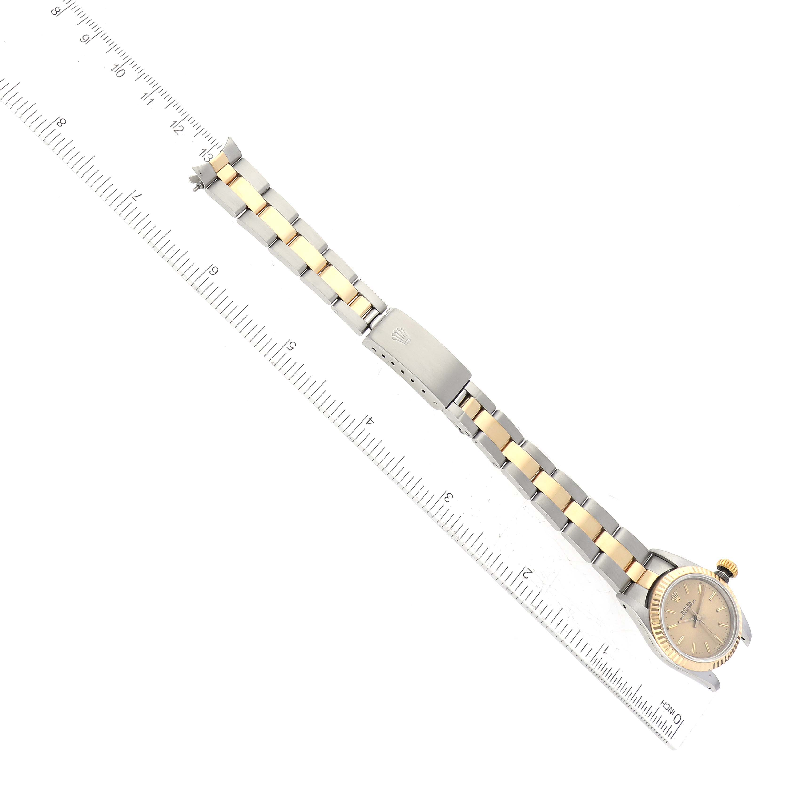 The image shows a top-down view of a Rolex Oyster Perpetual 67193 Women's Steel and Gold (two tone) Champagne Dial 67193 Women's Steel and Gold (two tone) Champagne Dial watch, displaying the full length of the bracelet against a ruler.