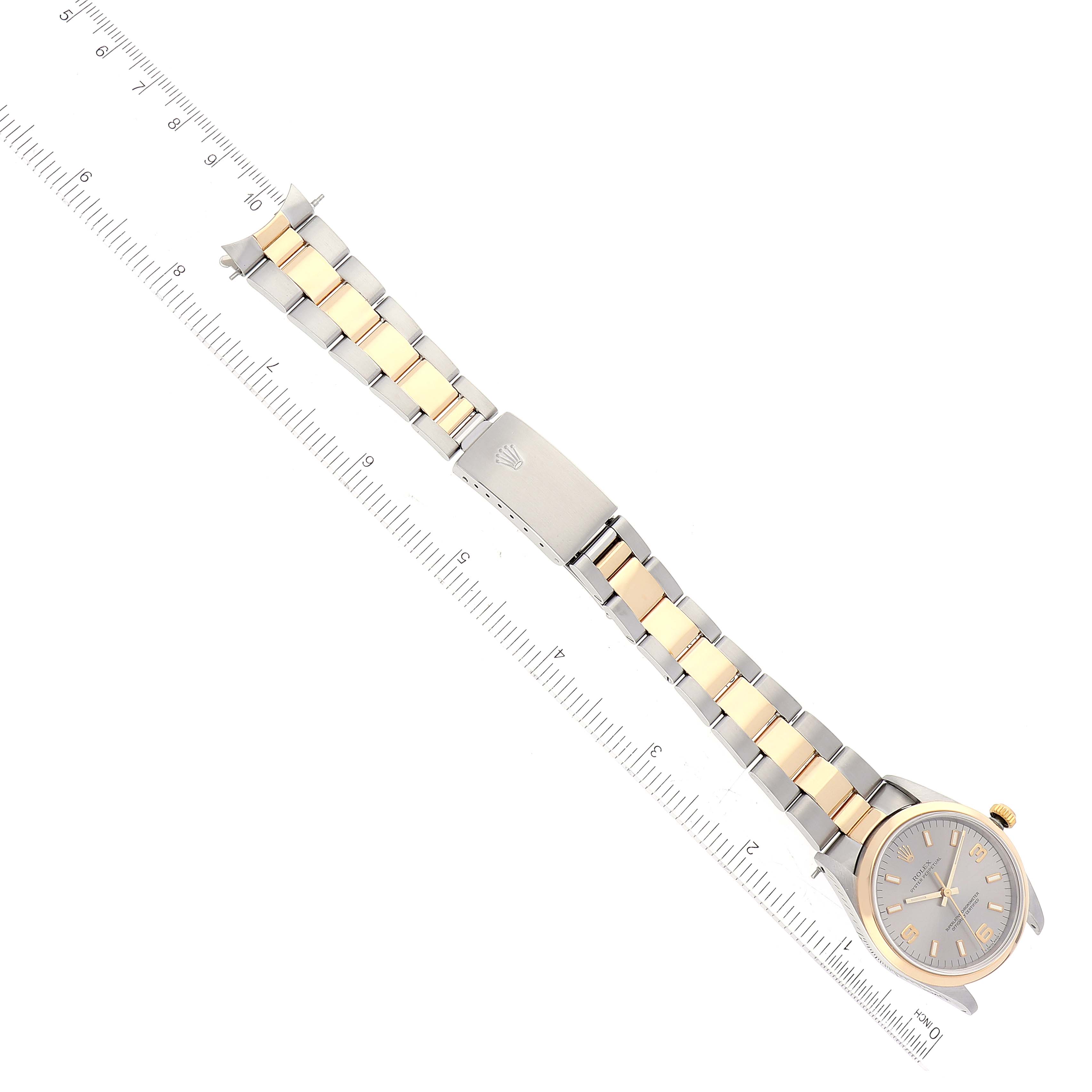 This image shows an overhead view of a Rolex Oyster Perpetual 14203 Men's Steel and Gold (two tone) Grey Dial 14203 Men's Steel and Gold (two tone) Grey Dial watch with a two-tone bracelet next to a ruler.