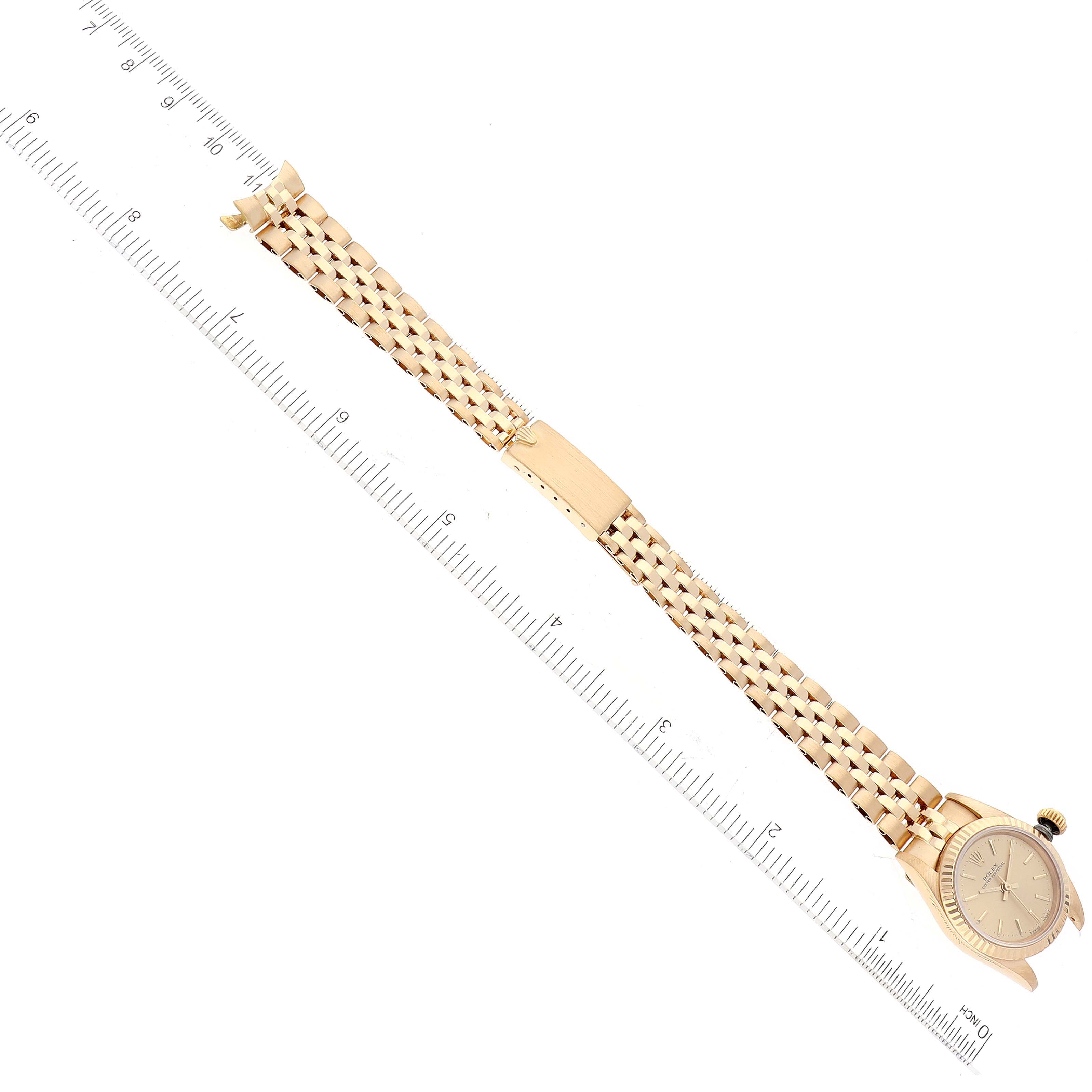 The image shows the entire Rolex President 67198 Women
s Yellow Gold Champagne Dial 67198 Women
s Yellow Gold Champagne Dial watch laid flat, with the face and bracelet aligned alongside a ruler for scale.