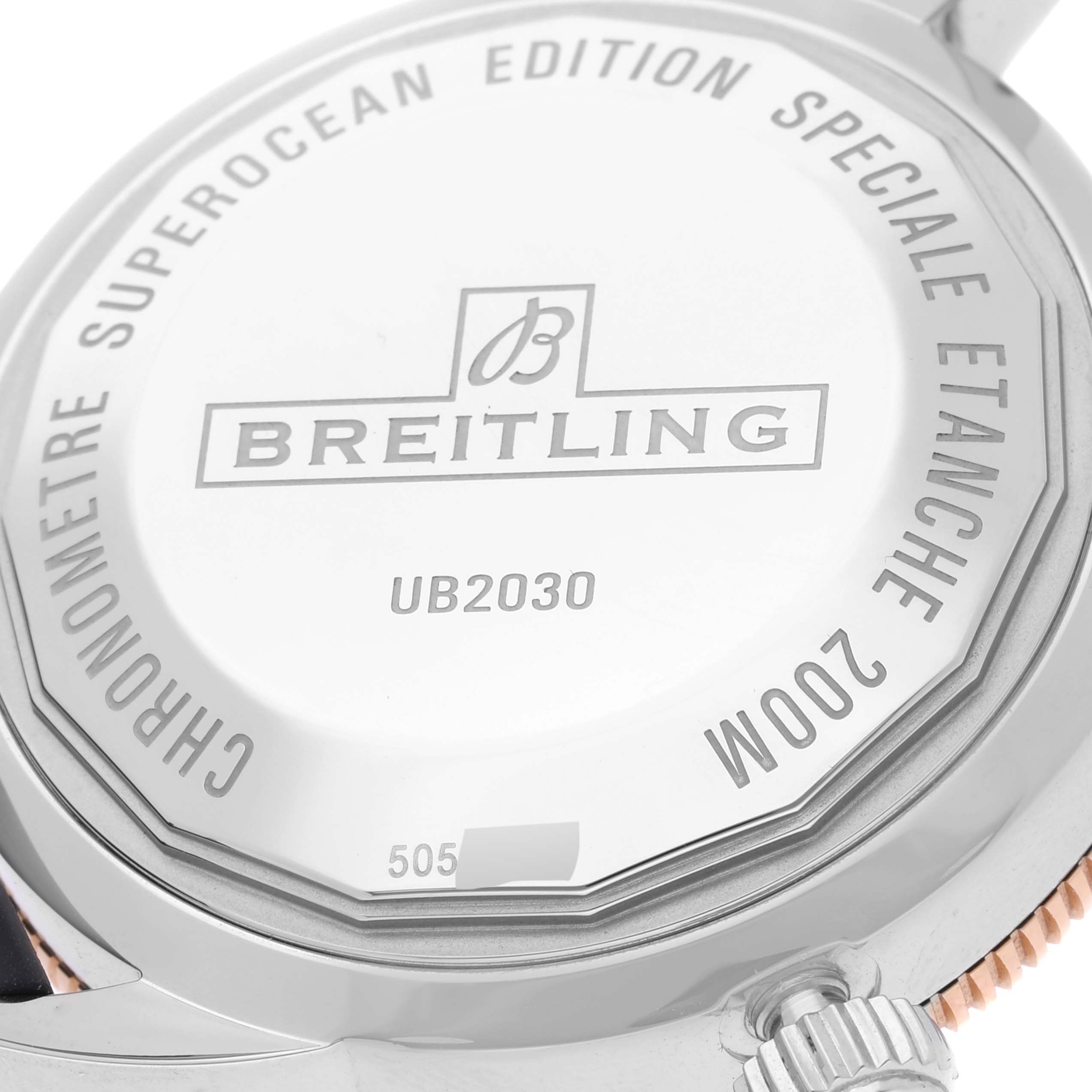 The image shows the back case of a Breitling Superocean UB2030121B1A1 Men's Stainless Steel Black Dial UB2030121B1A1 Men's Stainless Steel Black Dial watch, showcasing its inscriptions and the crown.