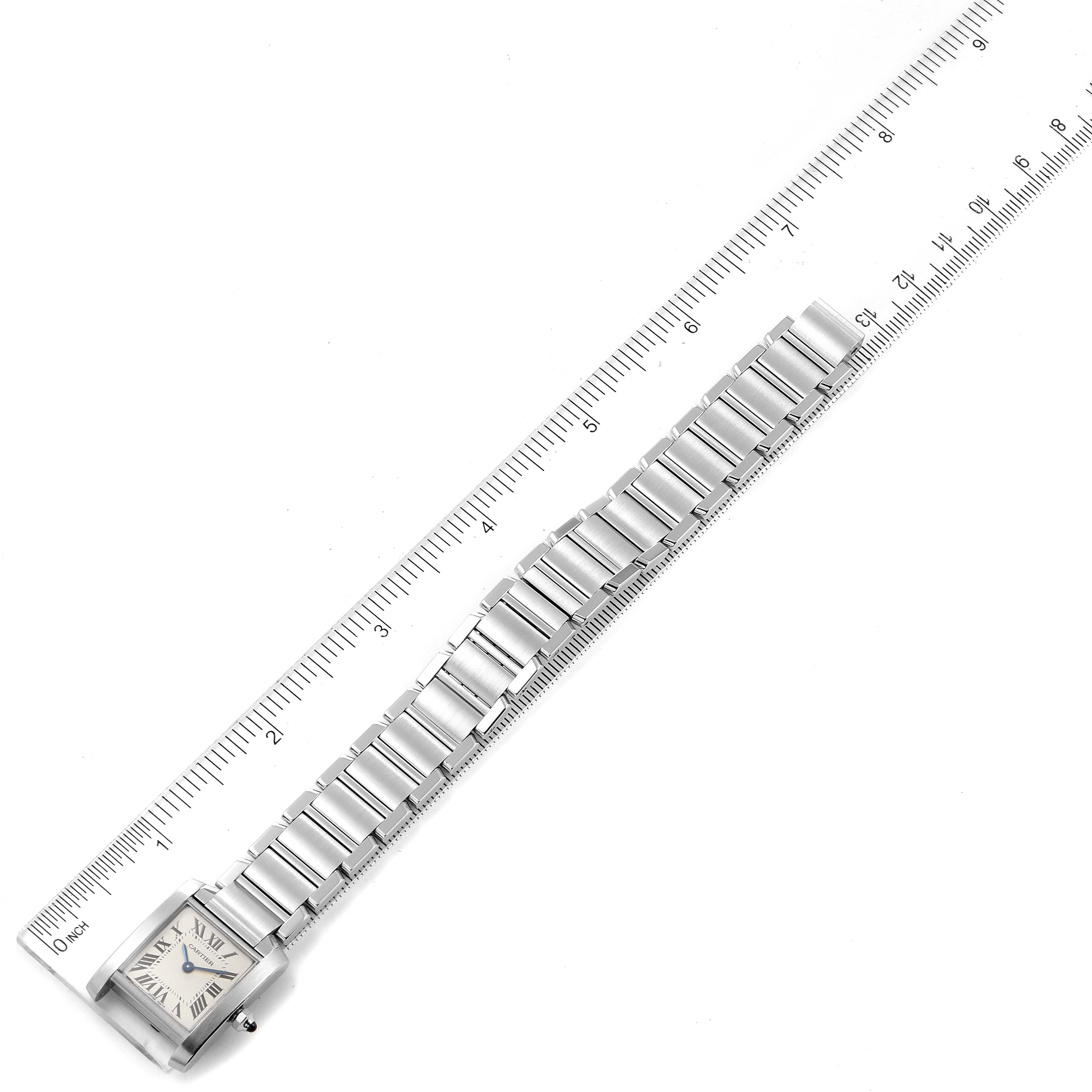 The image shows a Cartier Tank Française watch laid flat next to a ruler for measurement, showcasing its entire length and face.