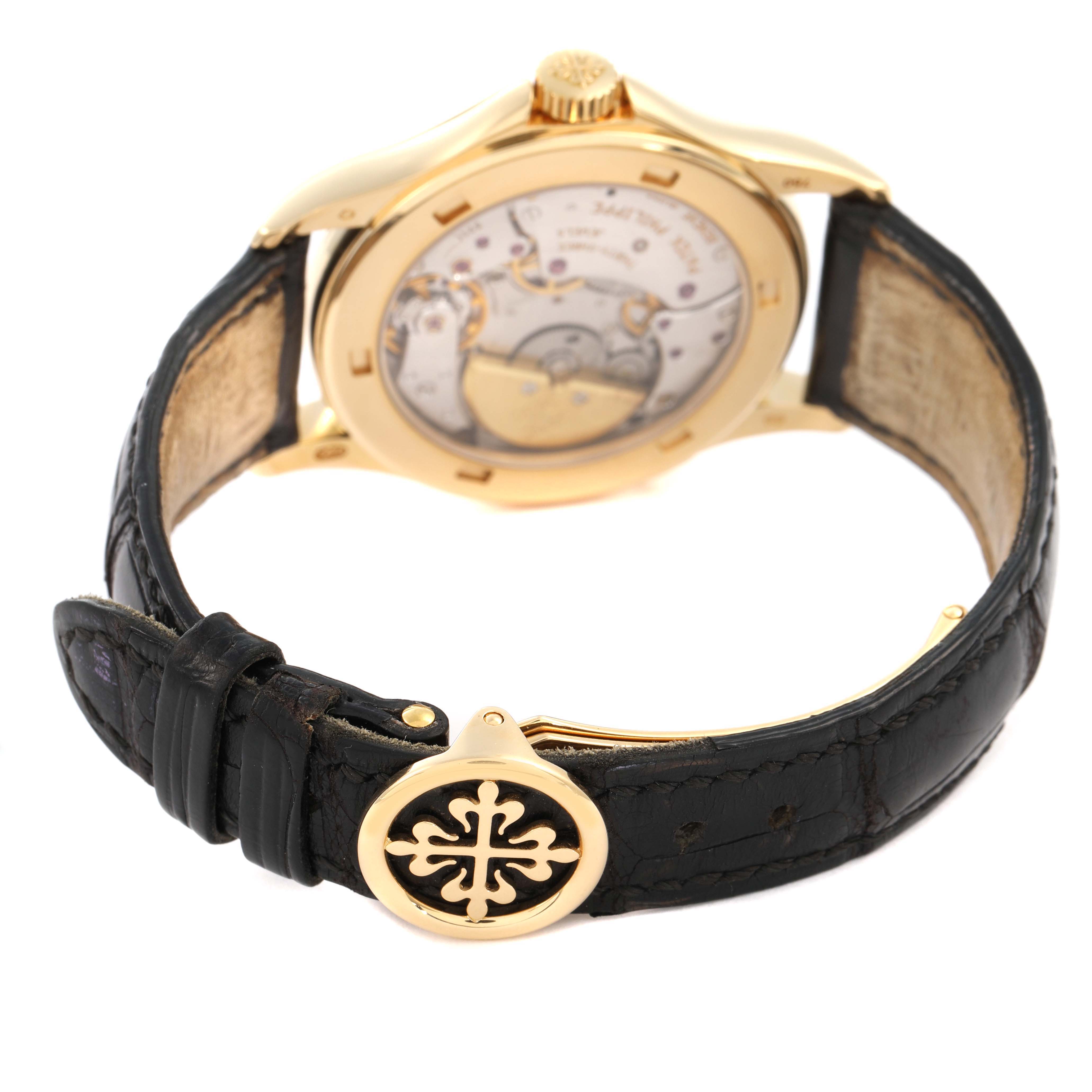 The Patek Philippe Complications 5110J-001 Men's Yellow Gold Silver Dial watch is shown from the back, highlighting its transparent case back and leather strap.