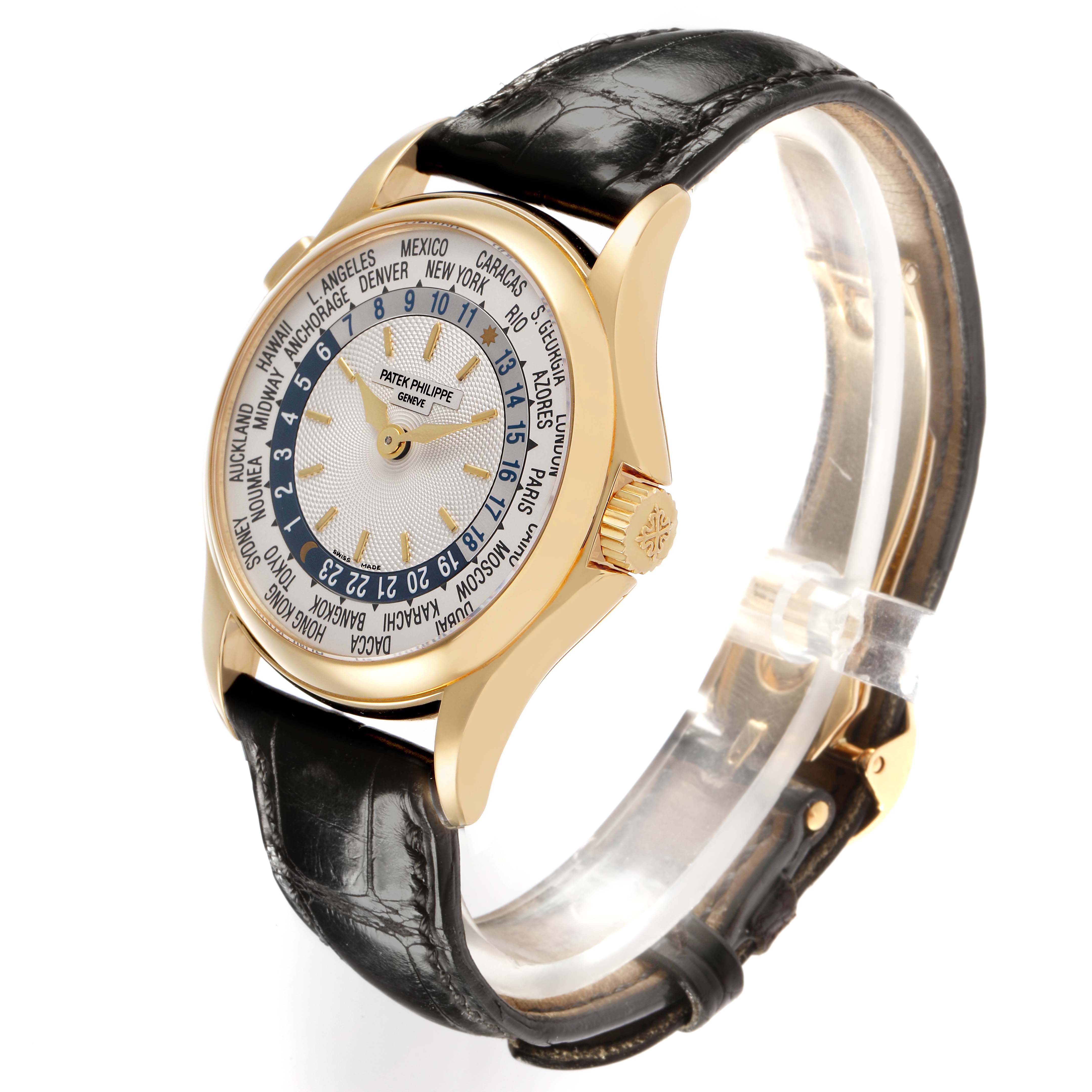 The Patek Philippe Complications 5110J-001 Men's Yellow Gold Silver Dial watch is shown at an angled side view, highlighting its gold case, world time dial, and leather strap.