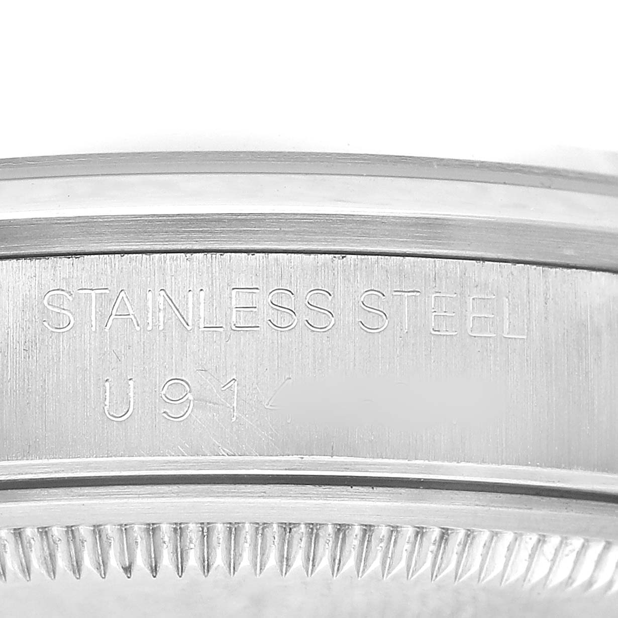 The image shows a close-up of the side of a Rolex Date 15200 Men's Stainless Steel Silver Dial watch, highlighting the "Stainless Steel" engraving.