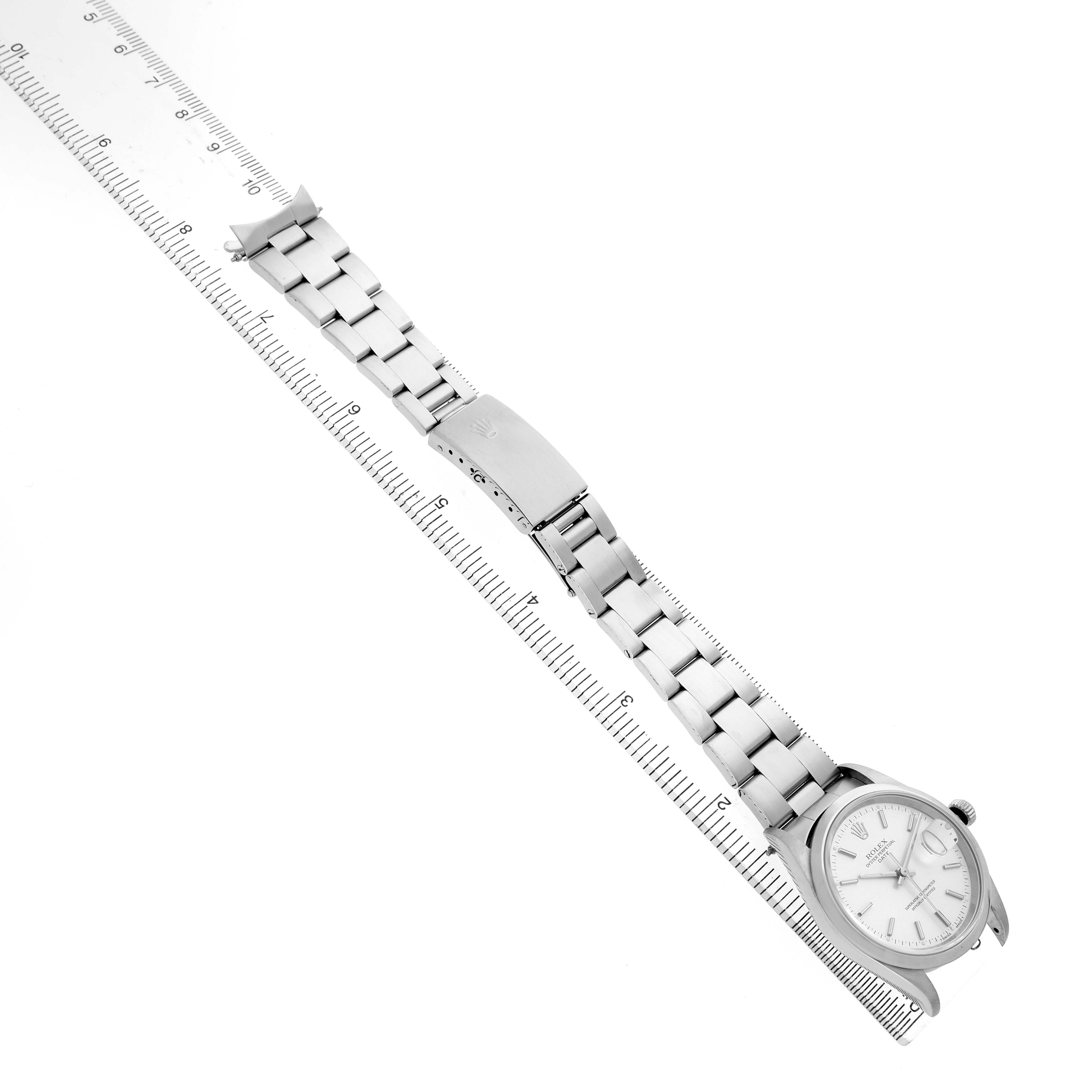 The image shows a side angle of a Rolex Date 15200 Men's Stainless Steel Silver Dial watch with a metal bracelet, next to a ruler for scale.