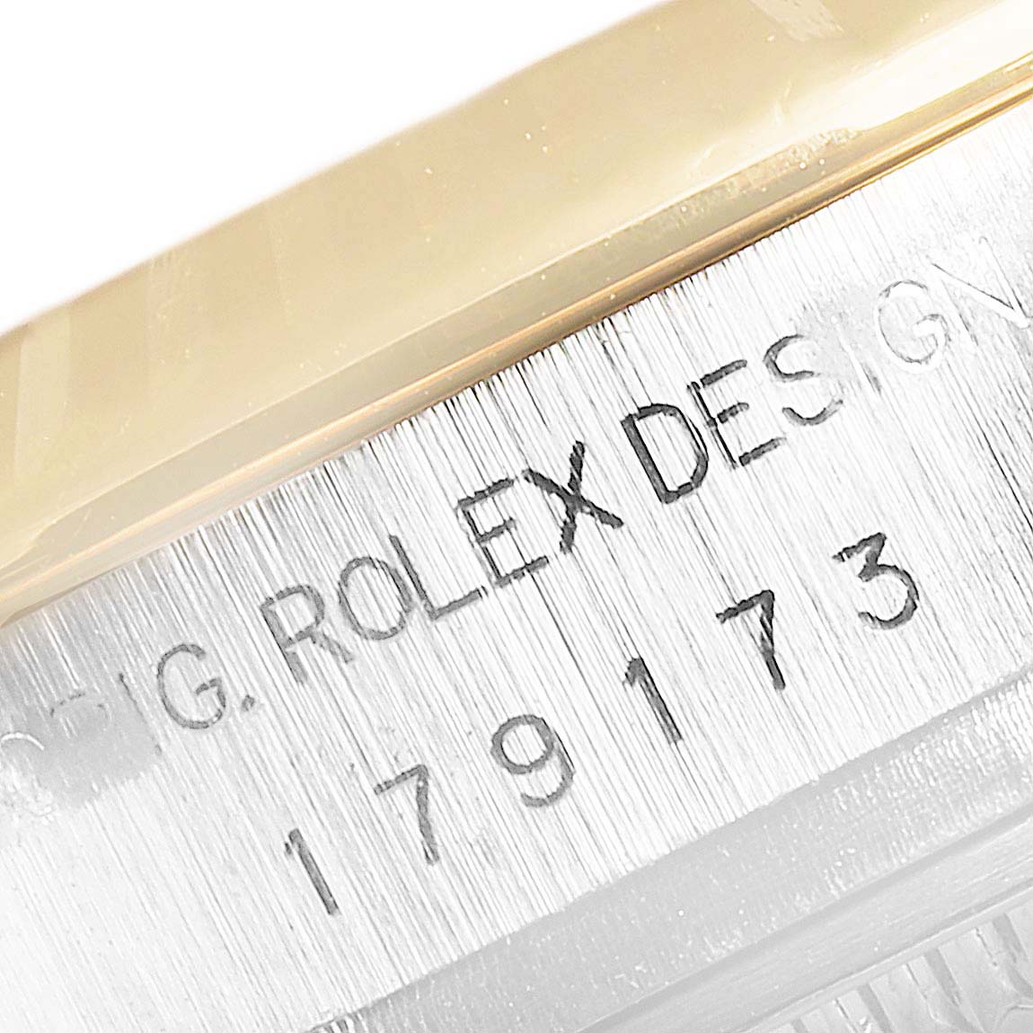 The image shows a close-up of the Rolex Datejust 179173 Women
s Steel and Gold (two tone) Champagne Dial 179173 Women
s Steel and Gold (two tone) Champagne Dial model
s case with engraved serial and design numbers.