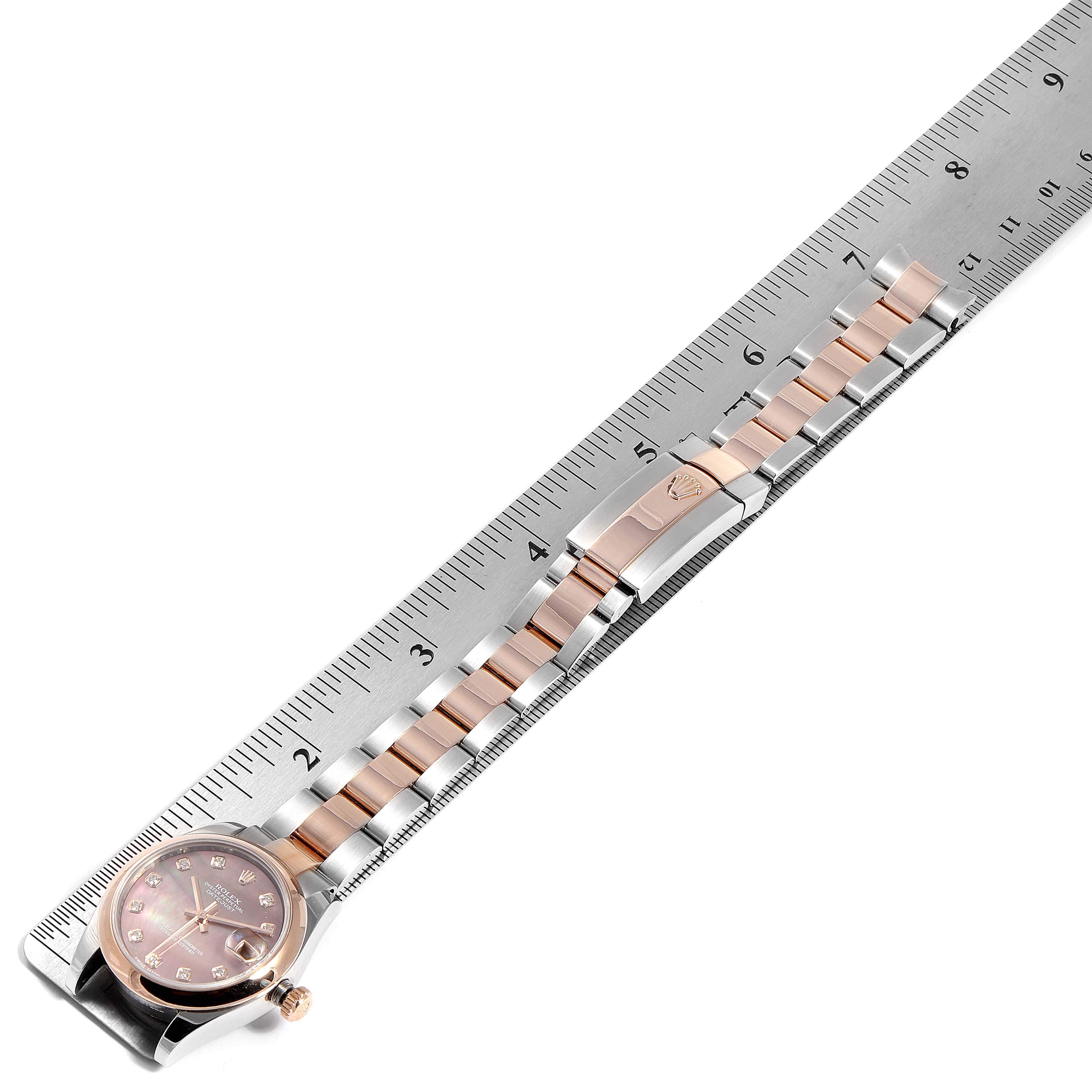 This image shows the front angle of a Rolex Mid-Size 178241 Women's Rose Gold Mother of Pearl Dial 178241 Women's Rose Gold Mother of Pearl Dial model watch laid alongside a ruler, highlighting its dial and bracelet.