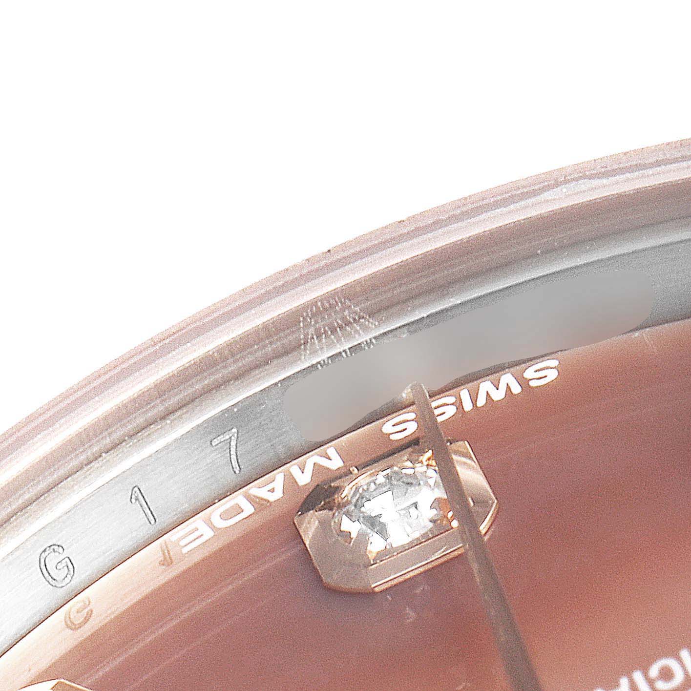 This close-up image shows part of the dial and inner bezel of a Mid-Size Rolex watch, featuring a diamond marker and "Swiss Made" text.