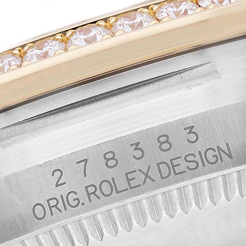 The image shows the bezel and the engraved case edge of a mid-size Rolex watch, focusing on its diamond-set design.