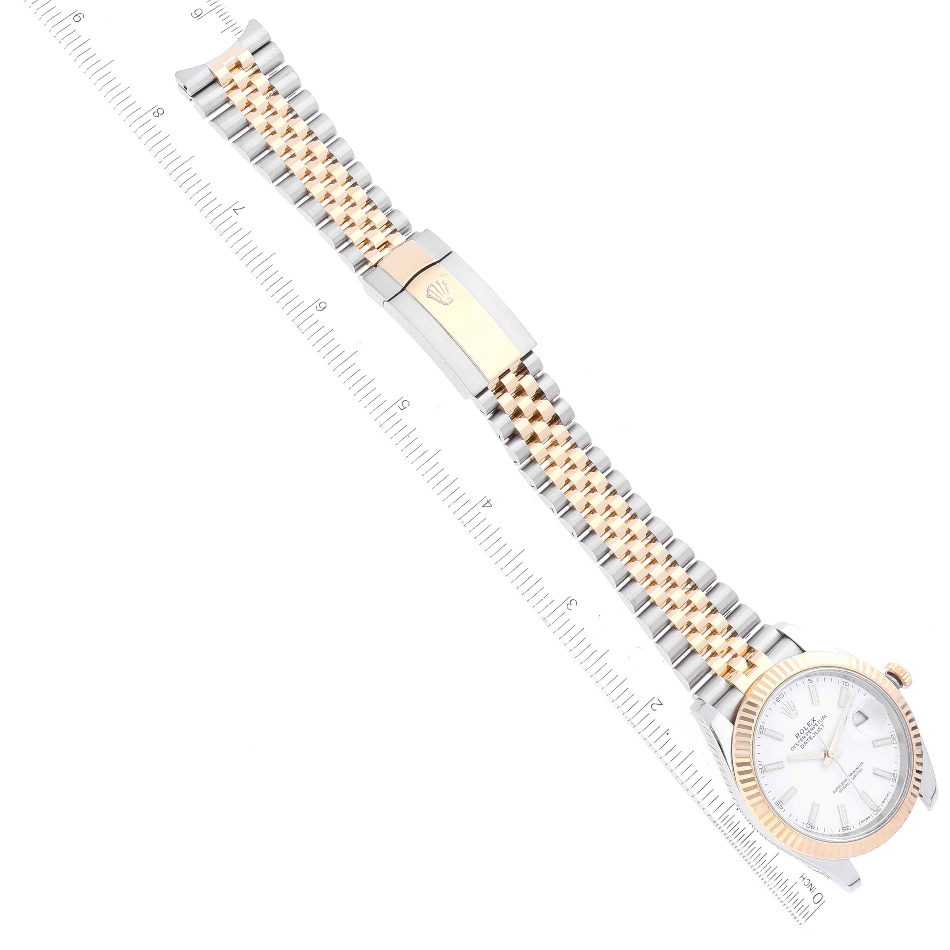 This image shows a top-down view of a Rolex Datejust 41 126333 Men's Steel and Gold (two tone) White Dial 126333 Men's Steel and Gold (two tone) White Dial watch with a silver and gold Jubilee bracelet alongside a ruler.