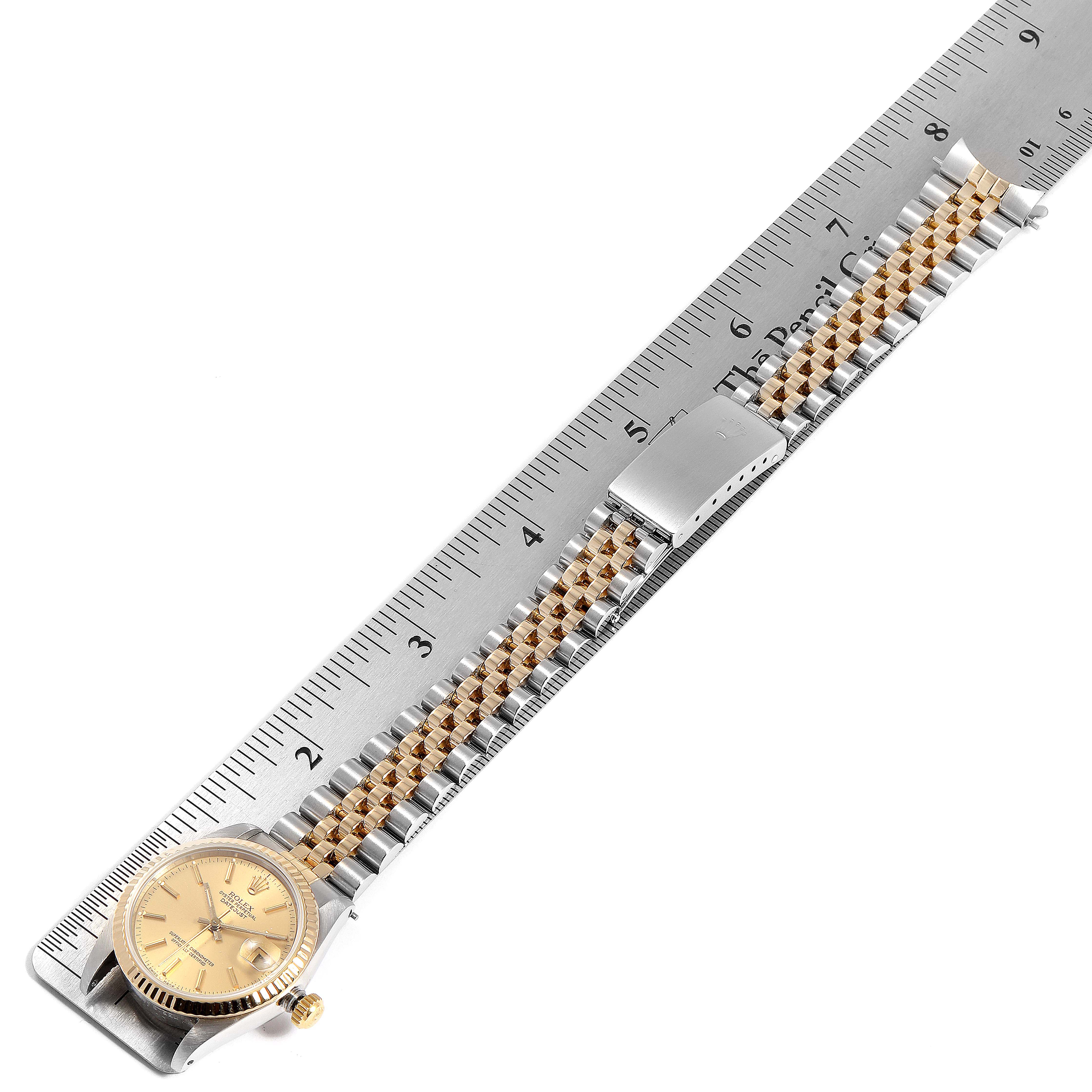 The image shows a Rolex Mid-Size 68273 Women
s Steel and Gold (two tone) Champagne Dial 68273 Women
s Steel and Gold (two tone) Champagne Dial watch with a two-tone bracelet, a gold case, and a clasp next to a measuring ruler.