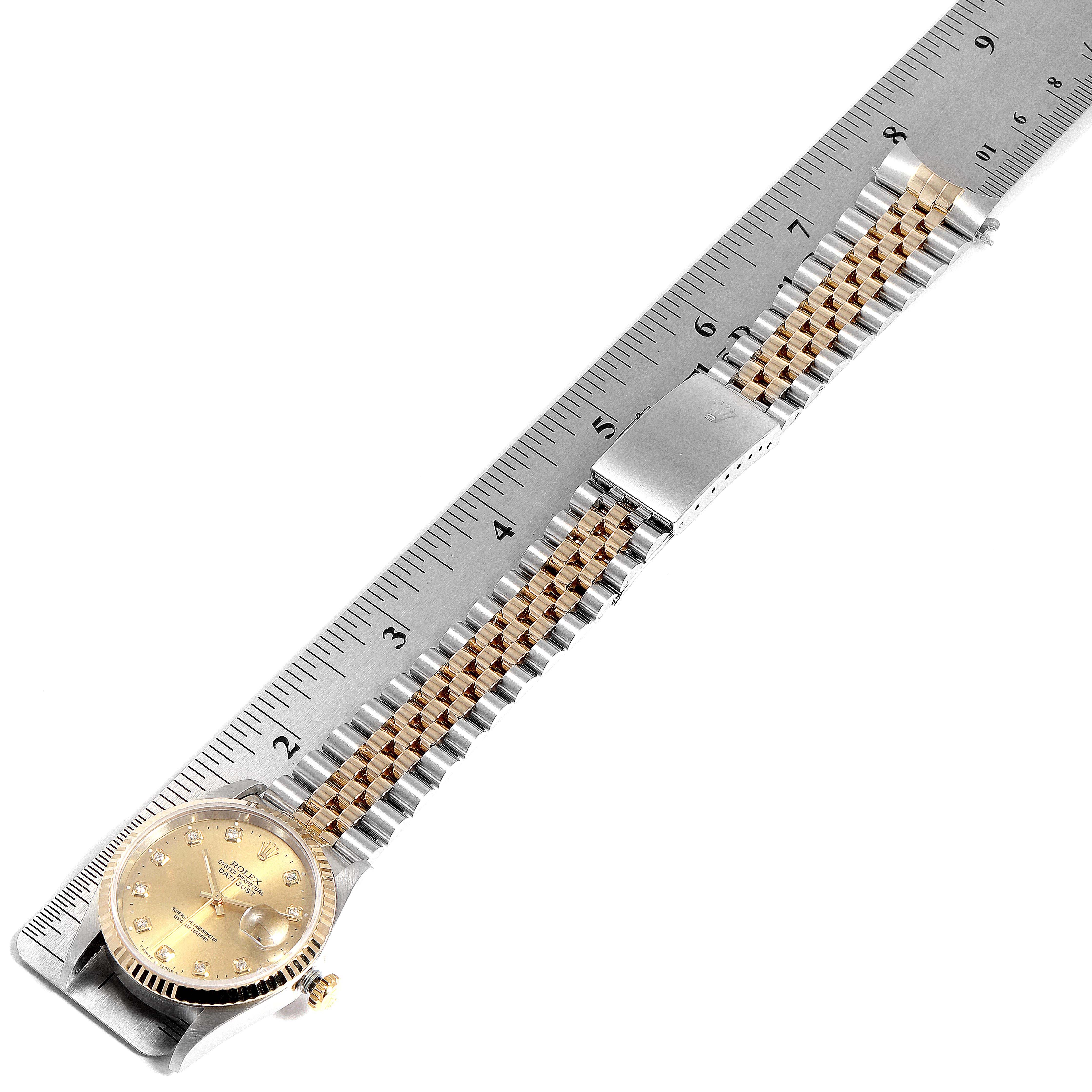 The image shows a top view of a Rolex Datejust 16233 Men
s Steel and Gold (two tone) Champagne Dial 16233 Men
s Steel and Gold (two tone) Champagne Dial watch with its bracelet extended along a ruler.