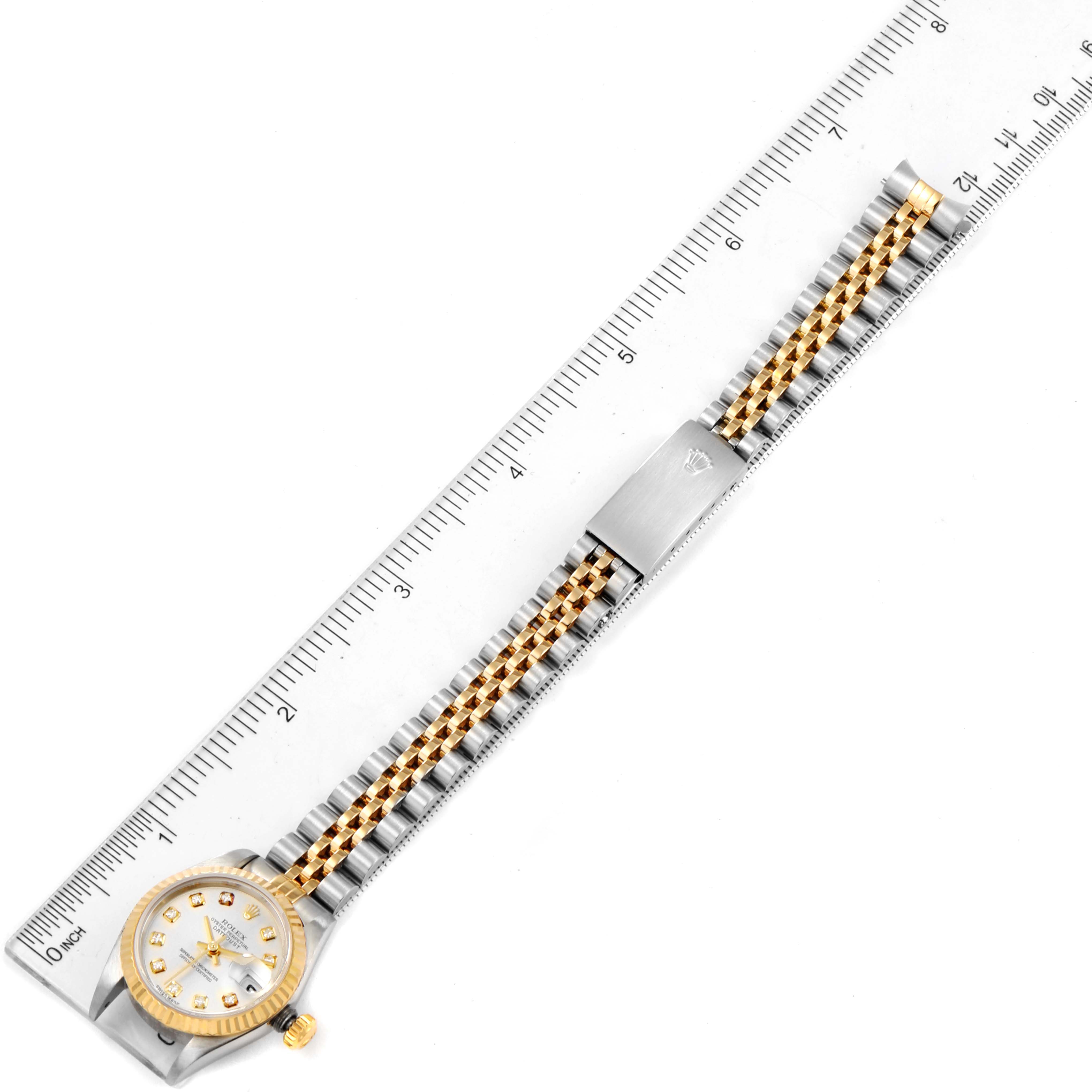 The Rolex Datejust 79173 Women's Steel and Gold (two tone) Silver Dial 79173 Women's Steel and Gold (two tone) Silver Dial watch is shown from a top-down angle with a full view of its face and bracelet, next to a ruler for scale.