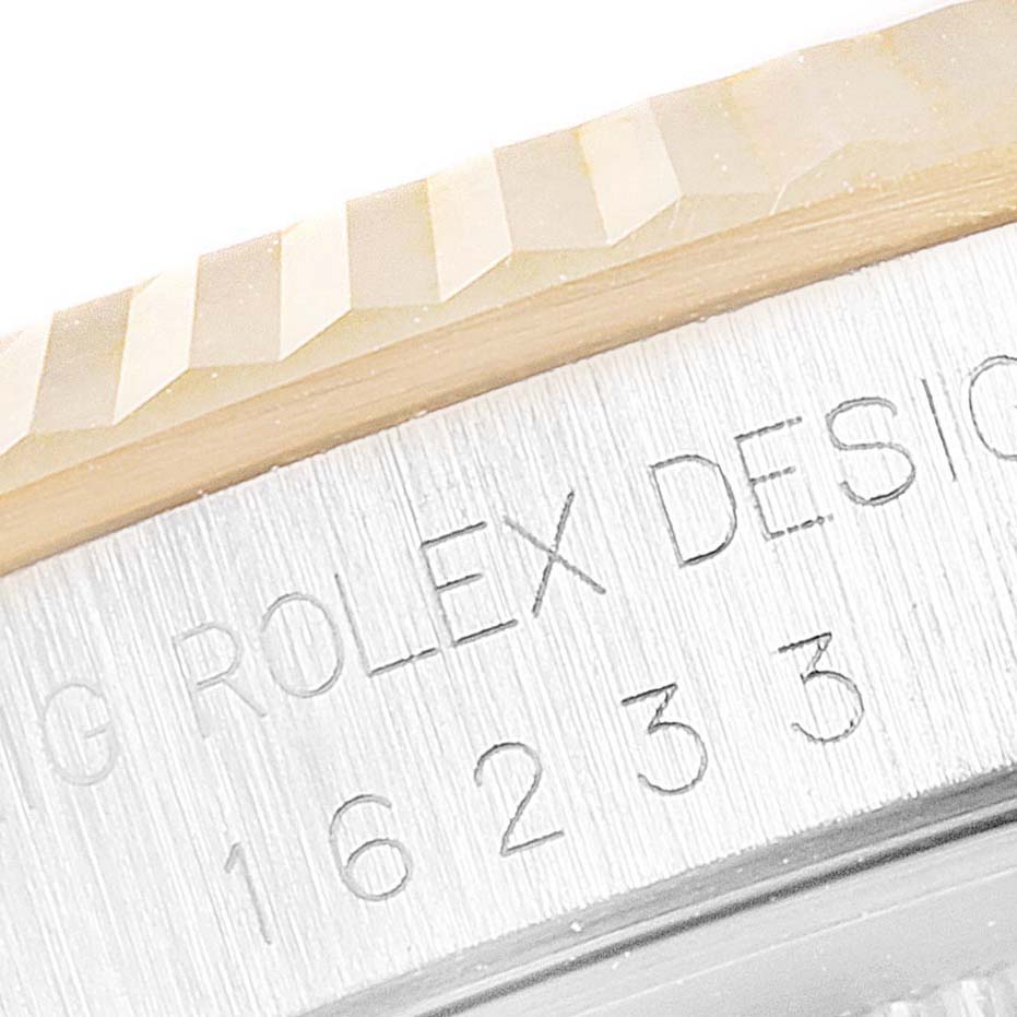 This close-up of a Rolex Datejust 16233 Men's Steel and Gold (two tone) White Dial 16233 Men's Steel and Gold (two tone) White Dial watch shows part of the fluted bezel and engraved reference numbers.