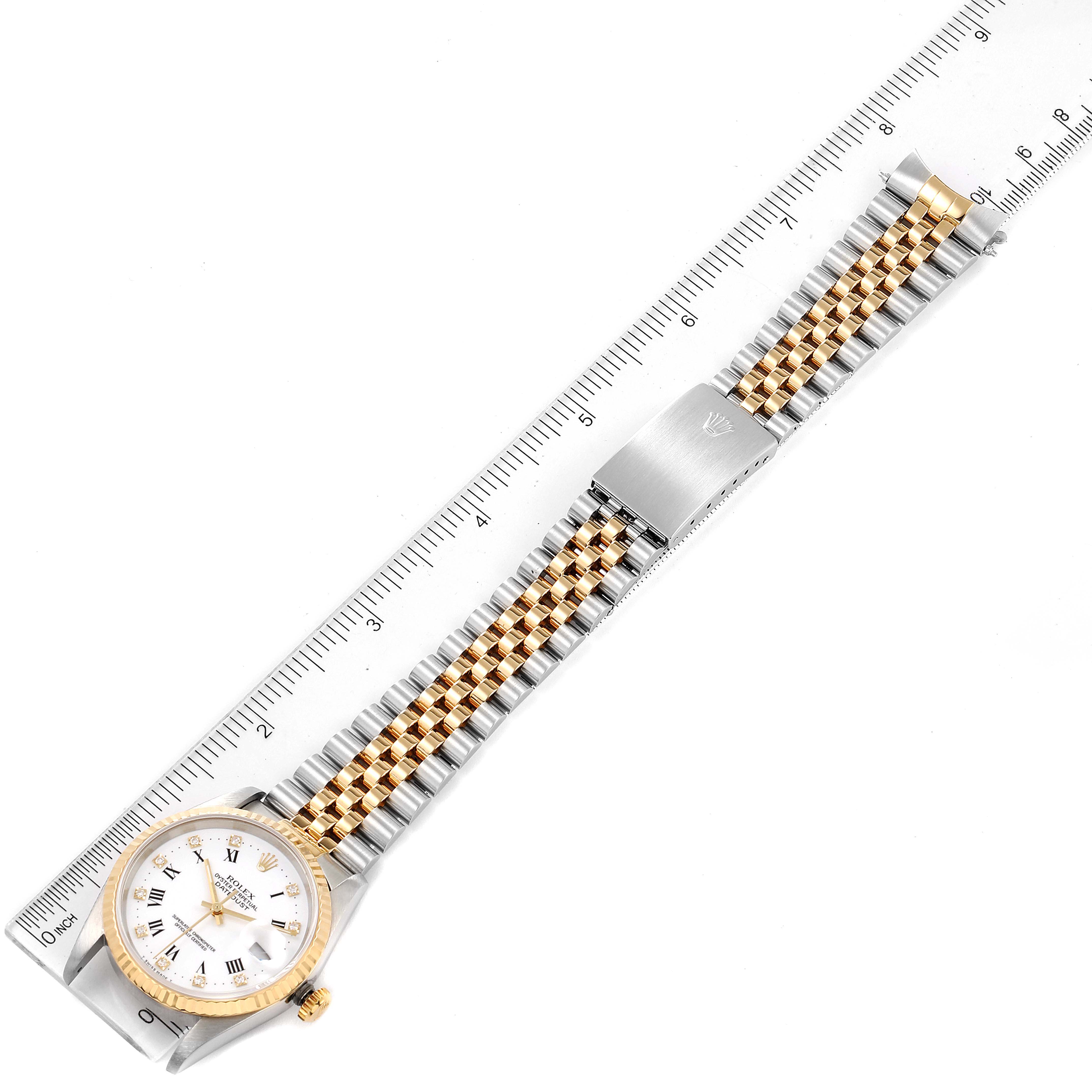 This image shows a Rolex Datejust 16233 Men's Steel and Gold (two tone) White Dial 16233 Men's Steel and Gold (two tone) White Dial watch laid flat along a ruler, showing its dial, case, and two-tone bracelet.