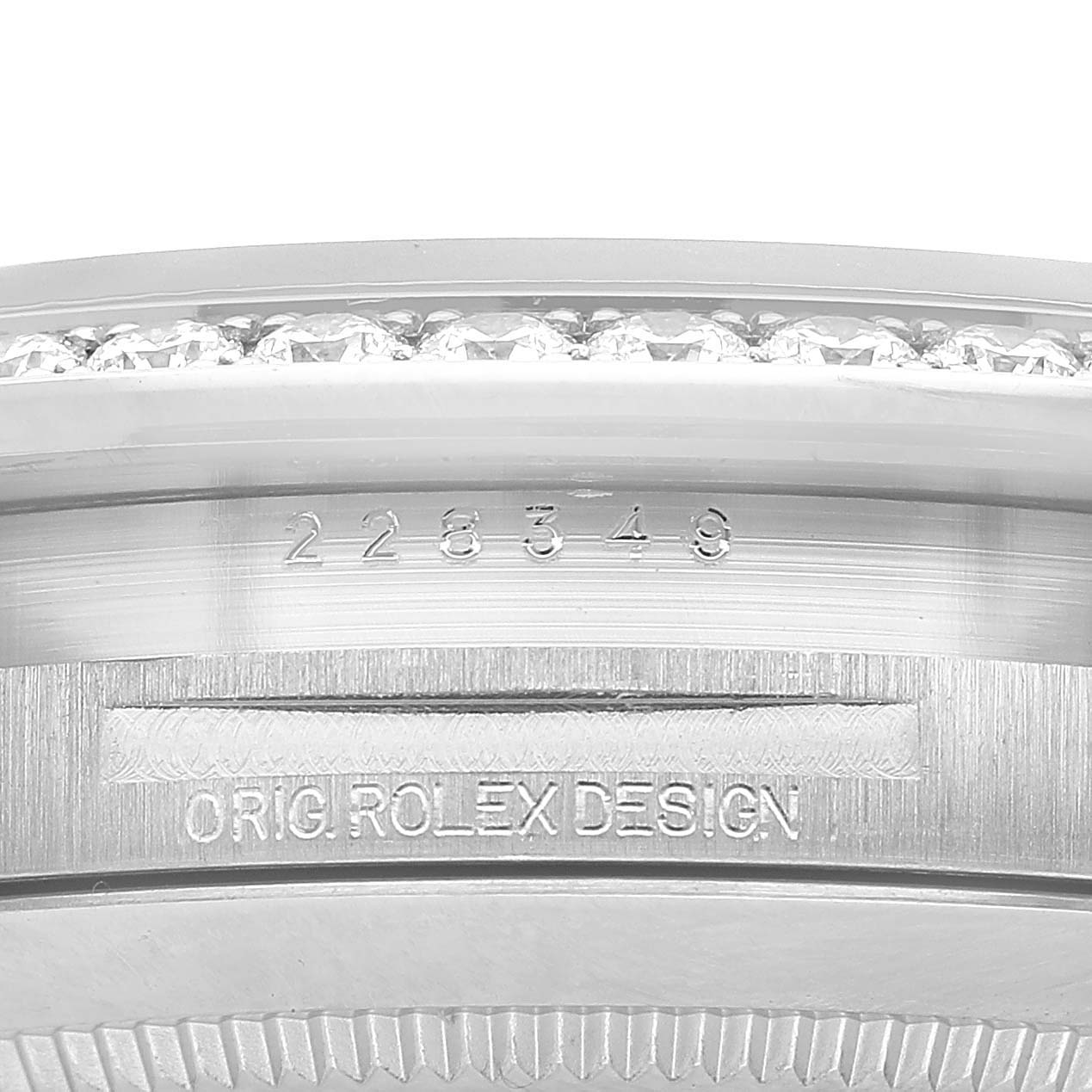 The image shows a close-up of the case side of a Rolex President 228349 Men's White Gold Silver Dial watch, featuring engraved text and a diamond-set bezel.
