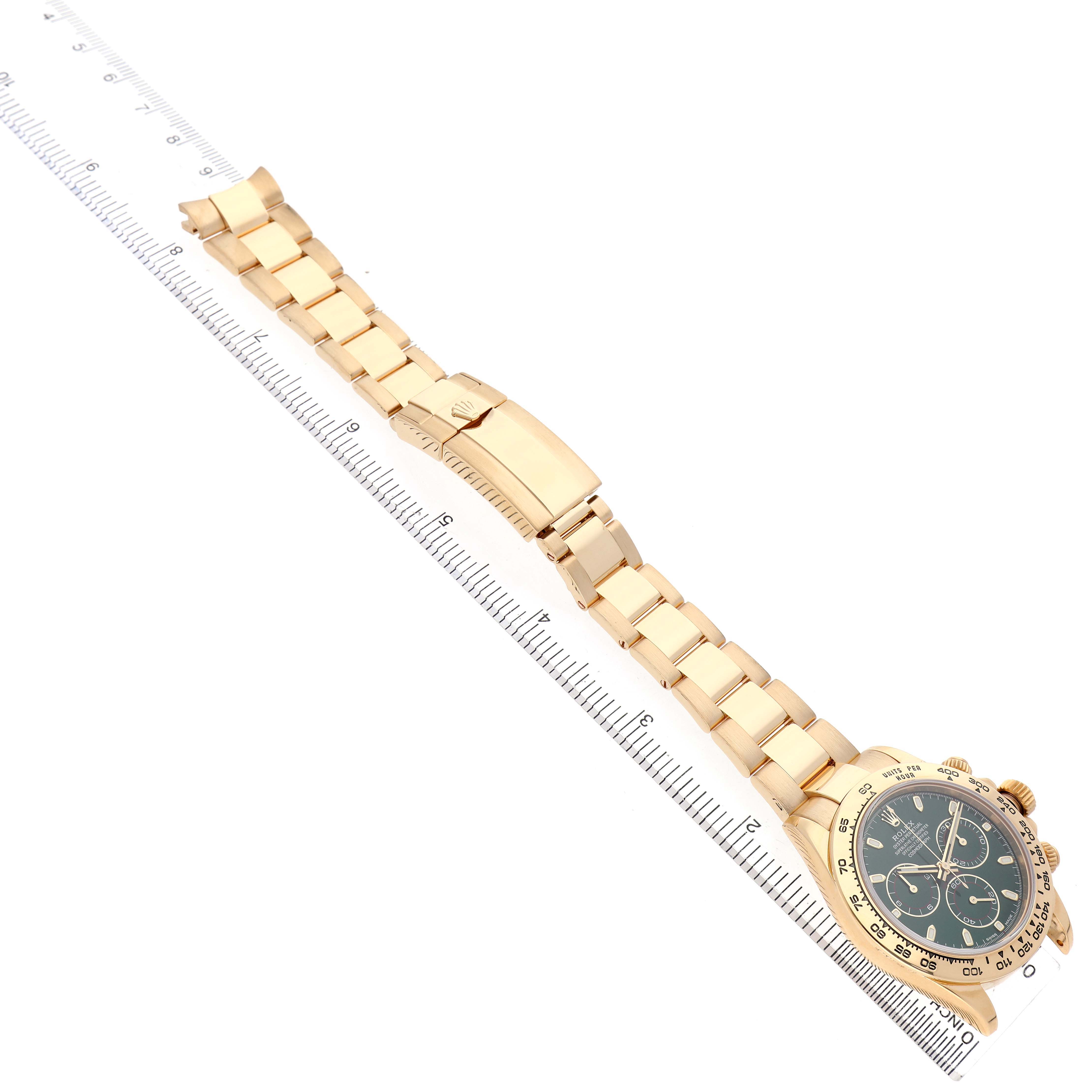 The Rolex Daytona 116508 Men's Yellow Gold Green Dial watch is displayed at an angle highlighting its bracelet, clasp, and dial, placed next to a measuring ruler.