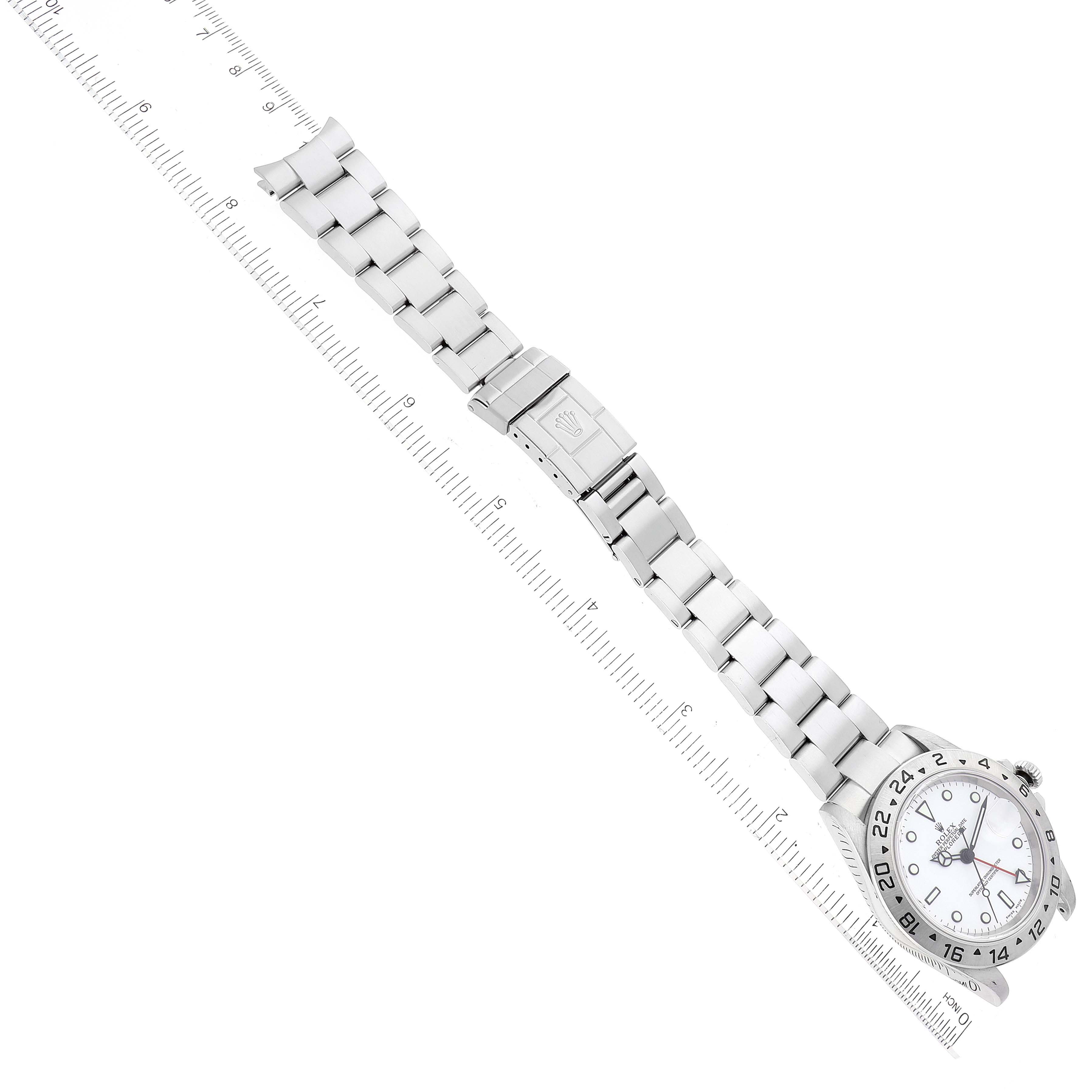 This image shows a top-down view of the Rolex Explorer 16570 Men's Stainless Steel White Dial 16570 Men's Stainless Steel White Dial watch and its metal bracelet, along with a ruler for scale.