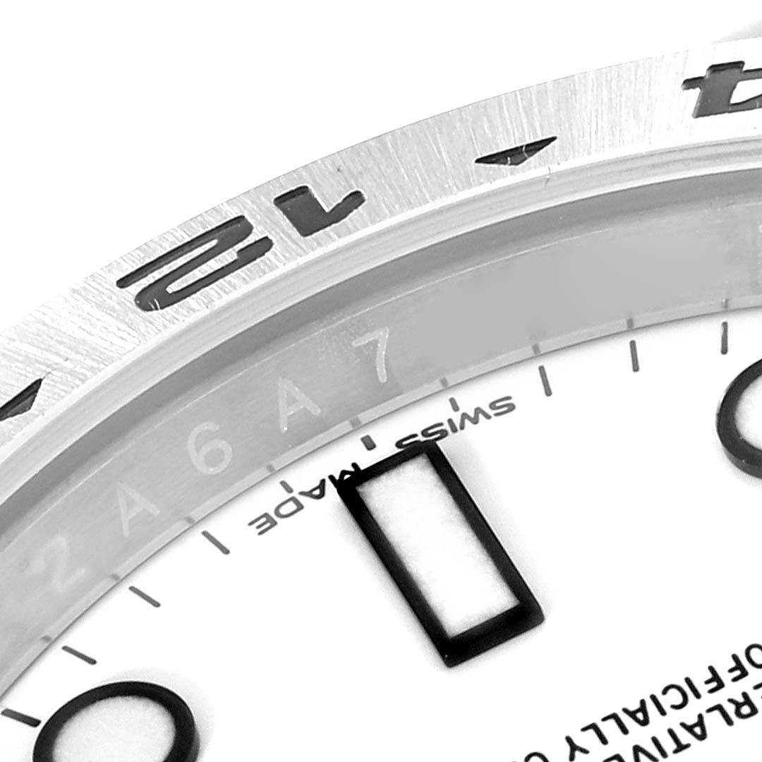 The image shows a close-up of the bezel and part of the dial of the Rolex Explorer 216570 Men
s Stainless Steel White Dial 216570 Men
s Stainless Steel White Dial watch, highlighting the 12 numerals and Swiss Made text.