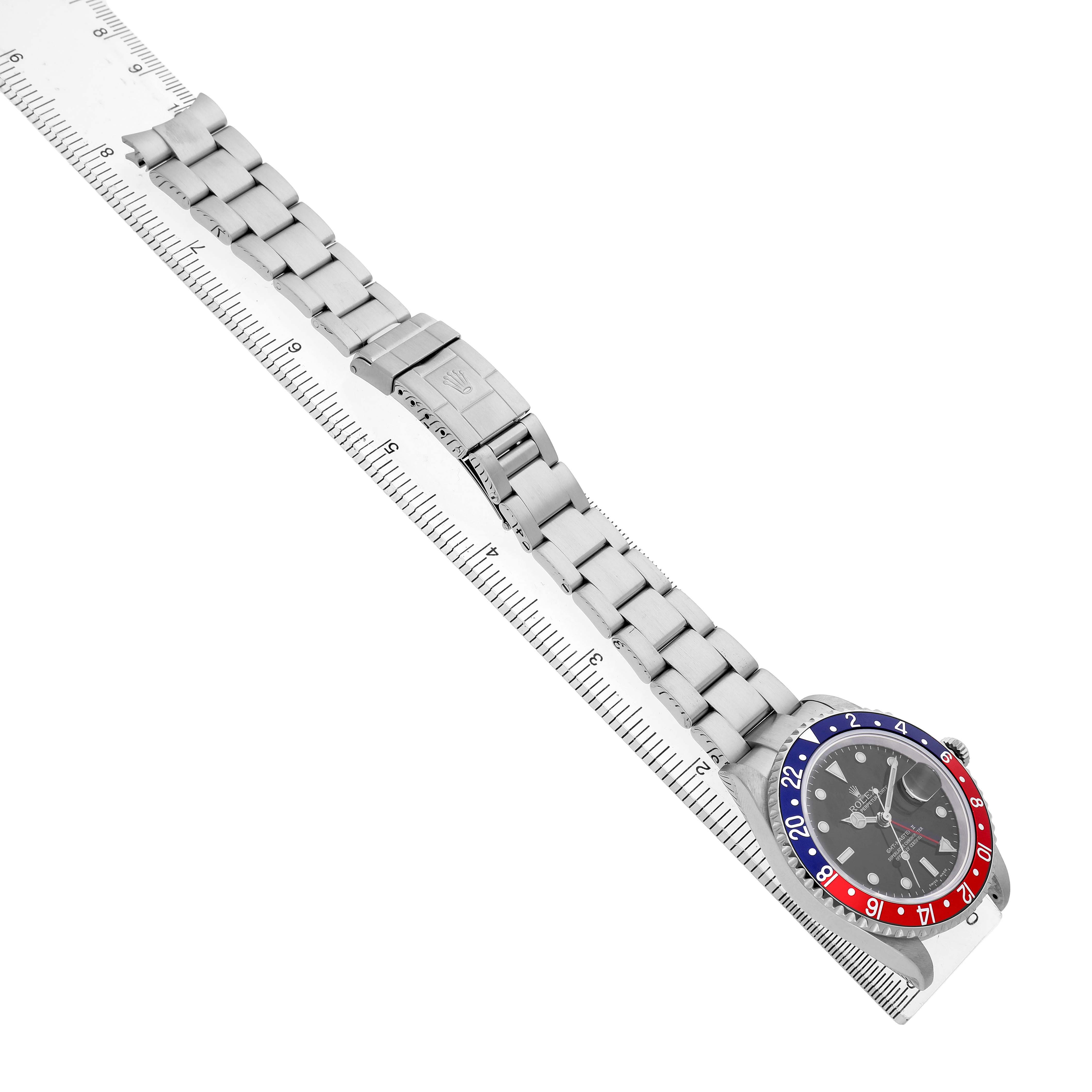 The Rolex GMT-Master 16710 Men's Stainless Steel Black Dial watch is shown at an angle displaying its bezel, face, and bracelet alongside a ruler.