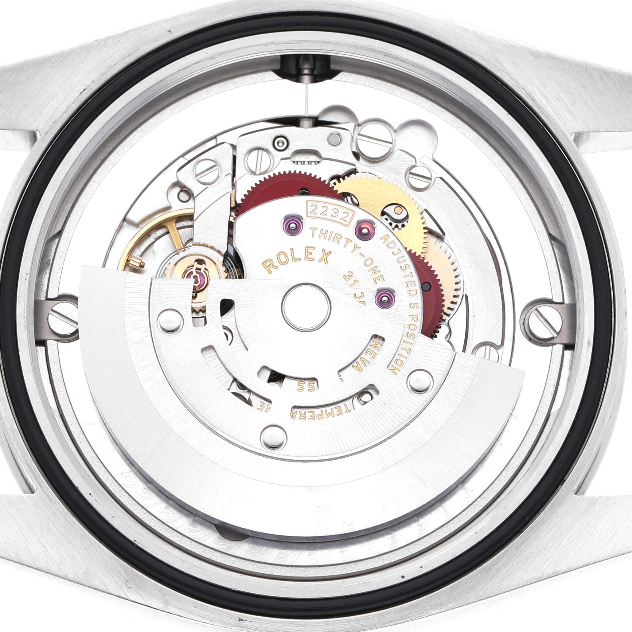 The image shows the internal mechanism of the Rolex Oyster Perpetual 124200 Men's Stainless Steel Black Dial watch from a back view, highlighting its movement and gears.