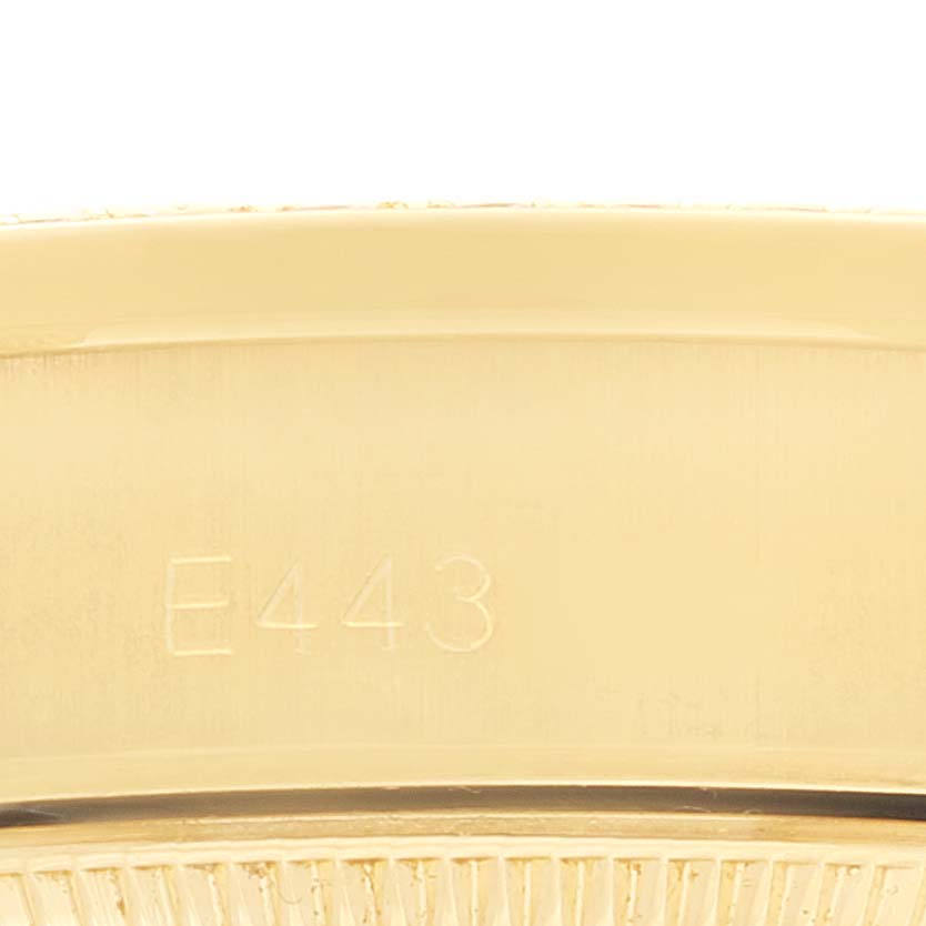 This close-up image shows a part of the Rolex President 69158 Women
s Yellow Gold Champagne Dial 69158 Women
s Yellow Gold Champagne Dial watch case with an engraving of "E443."