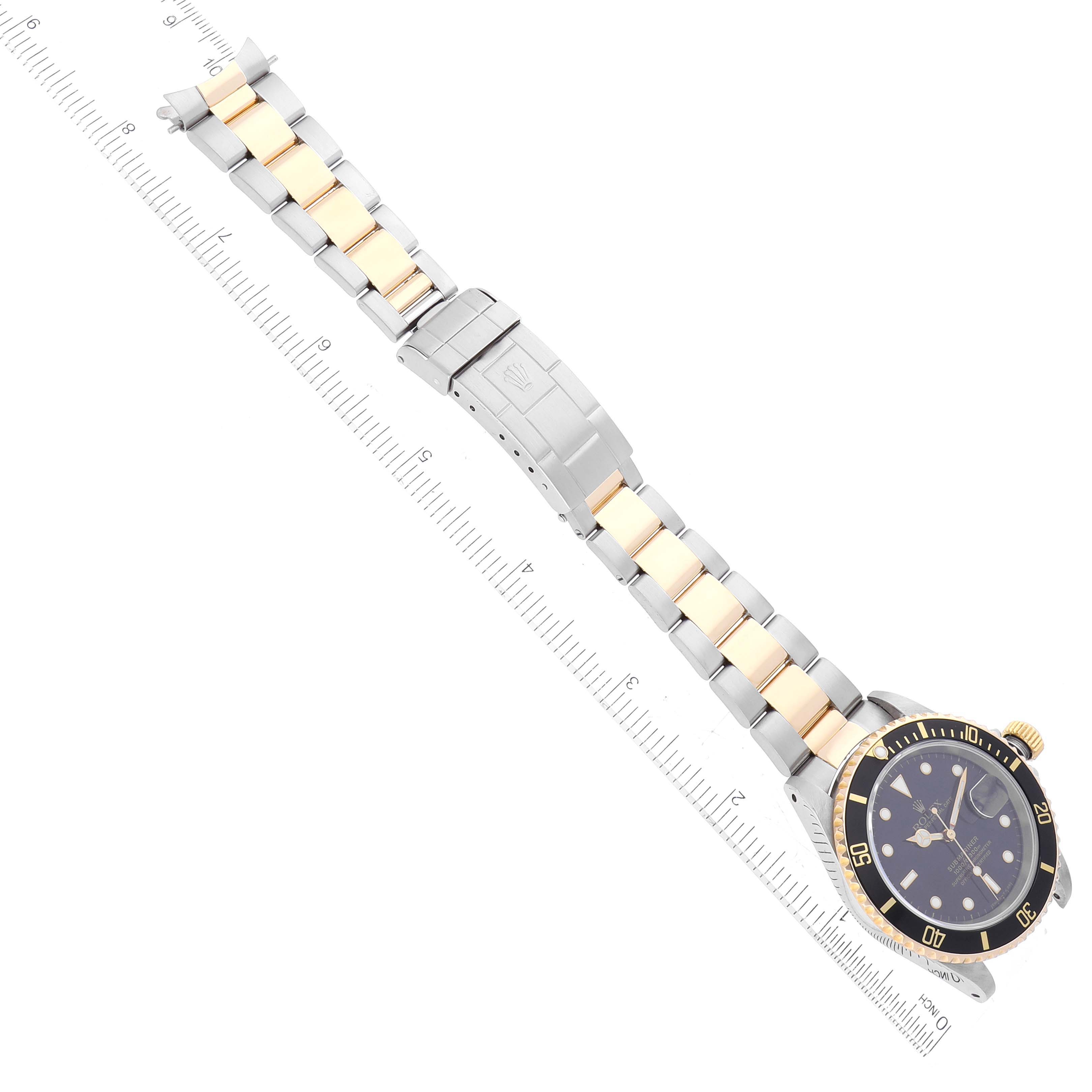 This image shows a top-down view of a Rolex Submariner 16613 Men
s Steel and Gold (two tone) Black Dial 16613 Men
s Steel and Gold (two tone) Black Dial watch, including the dial, bezel, and bracelet with a measuring scale alongside.