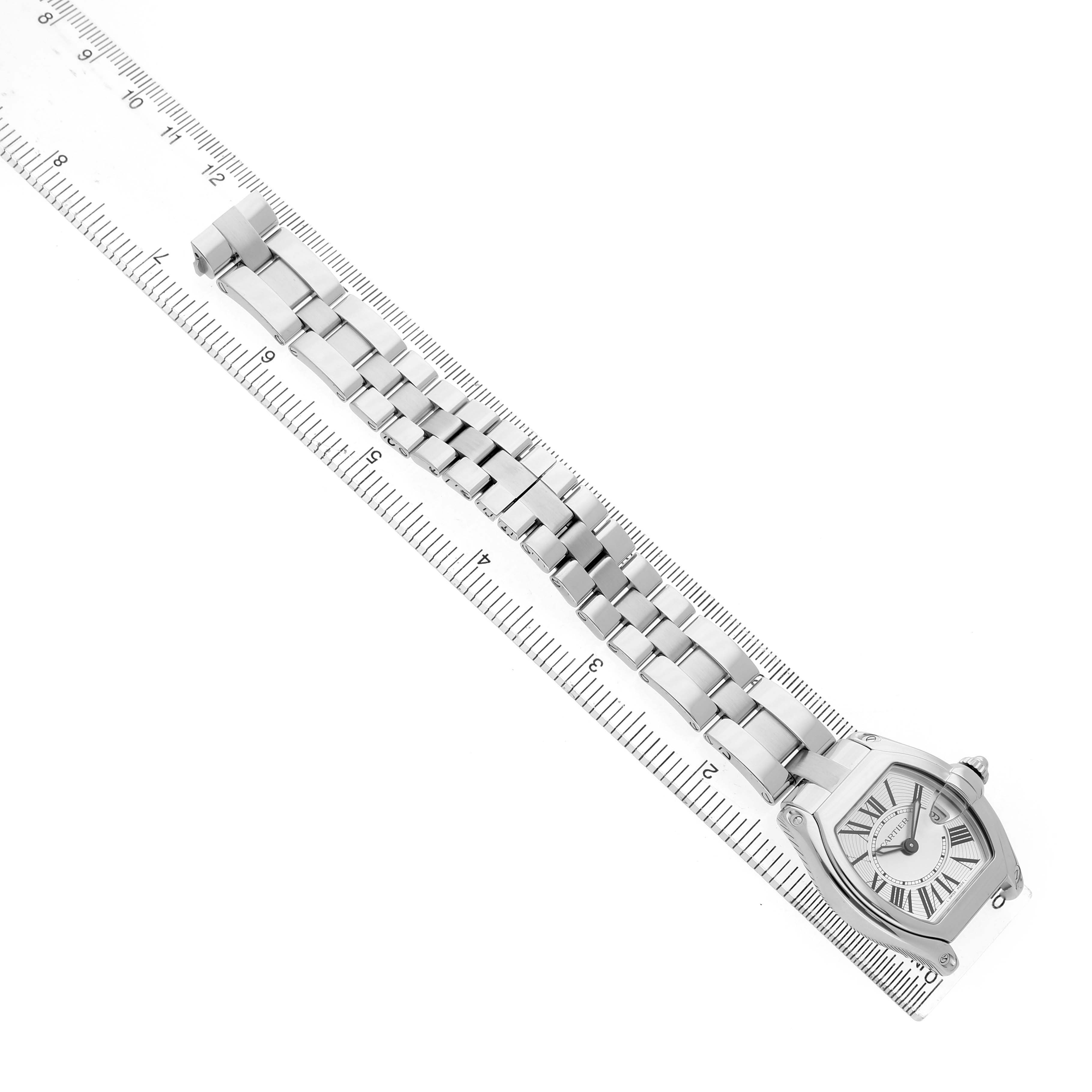 The Cartier Roadster W62016V3 Women's Stainless Steel Silver Dial watch is displayed diagonally, showing the face and full metal bracelet alongside a ruler for scale.