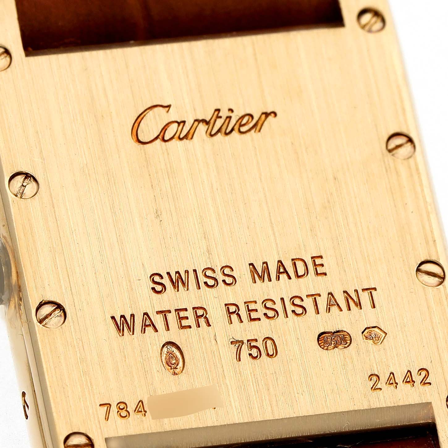 The image shows the back casing of a Cartier Tank Louis W1529856 Women's Yellow Gold Silver Dial watch with engraved details and screws visible.