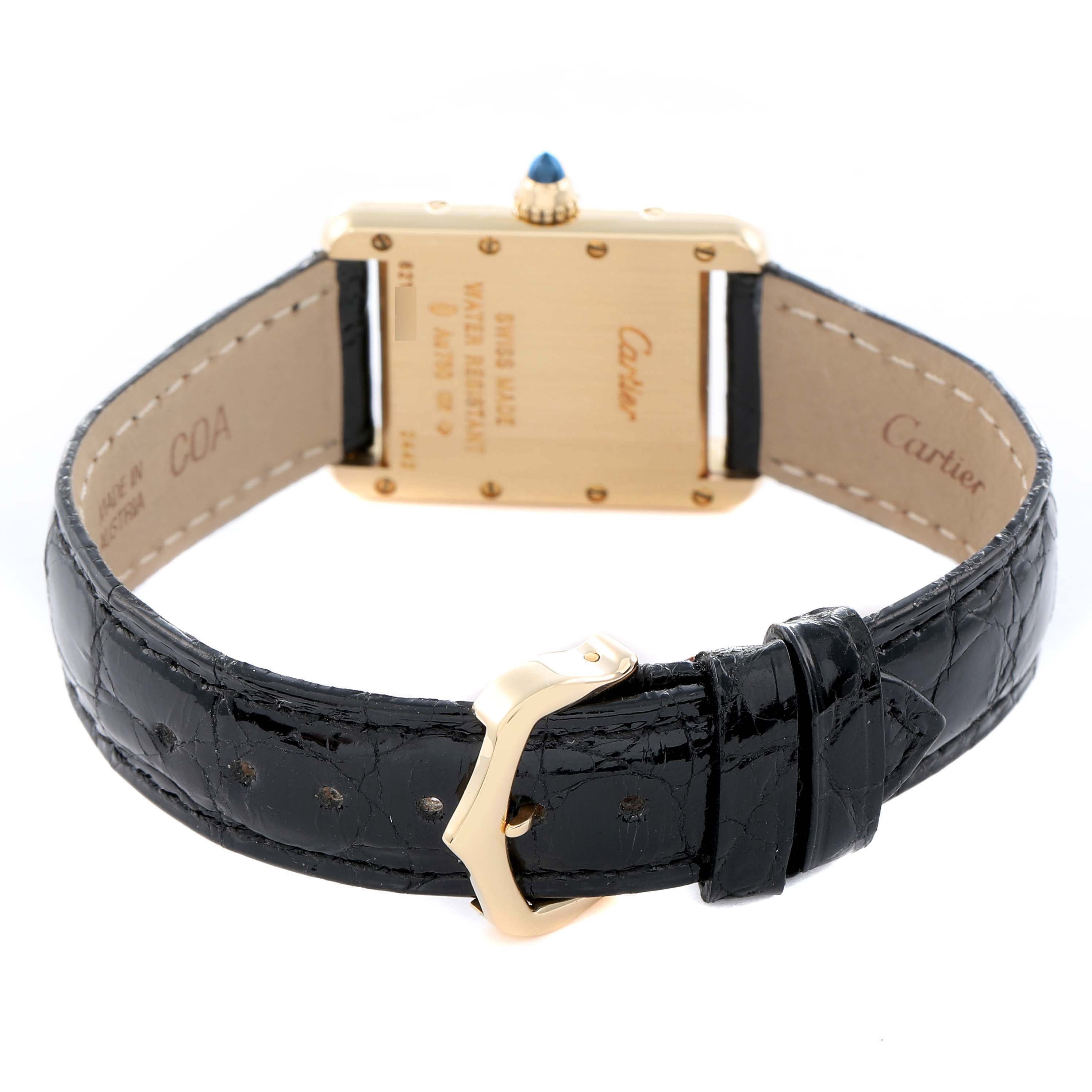 The image shows the back of a Cartier Tank Louis W1529856 Women's Yellow Gold Silver Dial watch with its gold case, blue cabochon crown, and black leather strap.